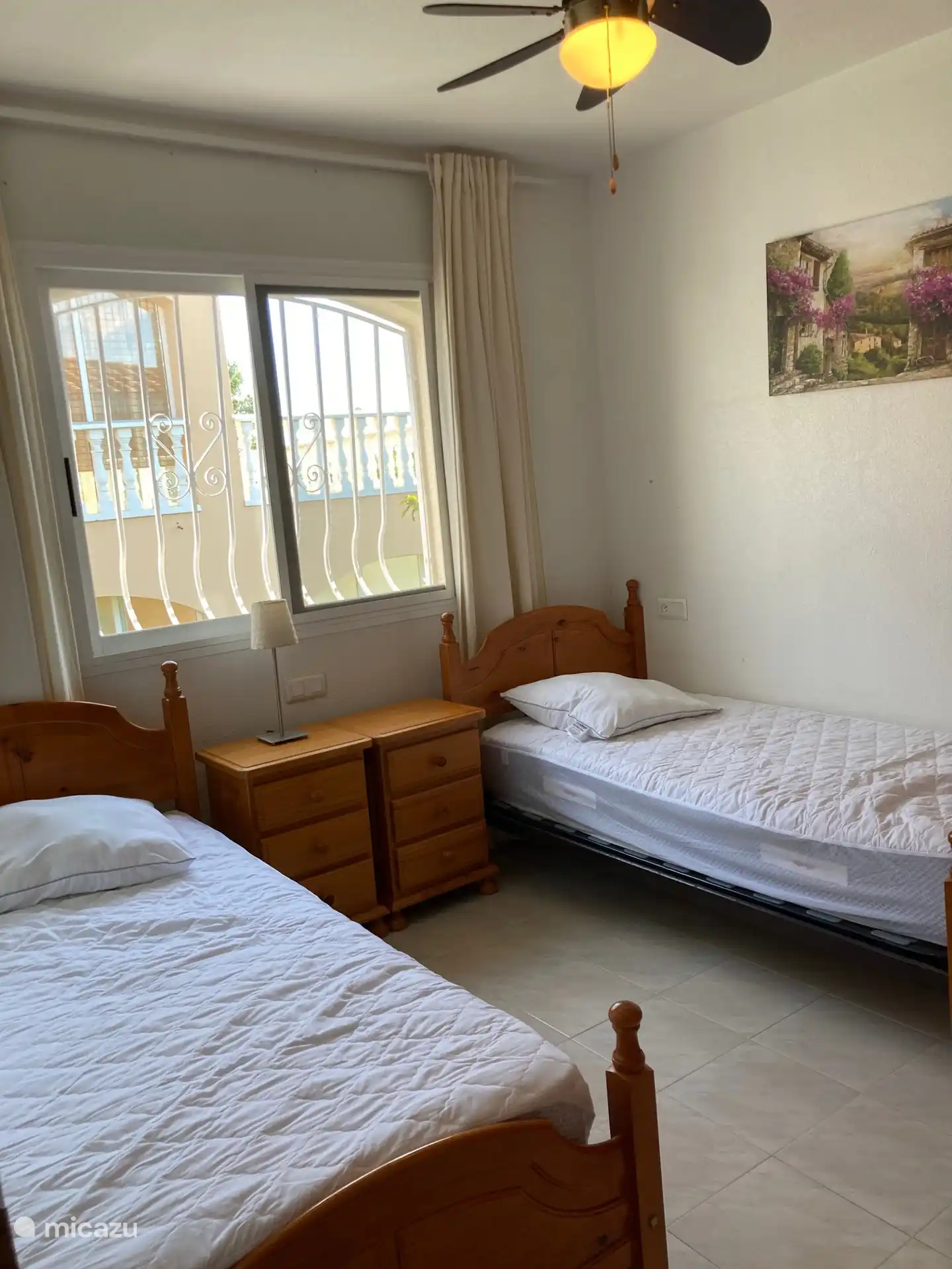 Spacious bedroom with two single beds, bedside tables, a spacious built-in wardrobe and ceiling fan.