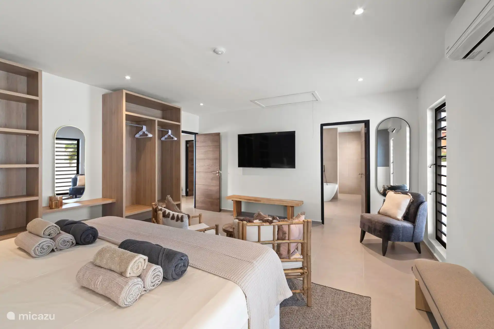 De master slaapkamer gezien vanuit de bedden van ieder 1 meter breed. Grote kledingkasten, airco, grote tv en extra zitjes