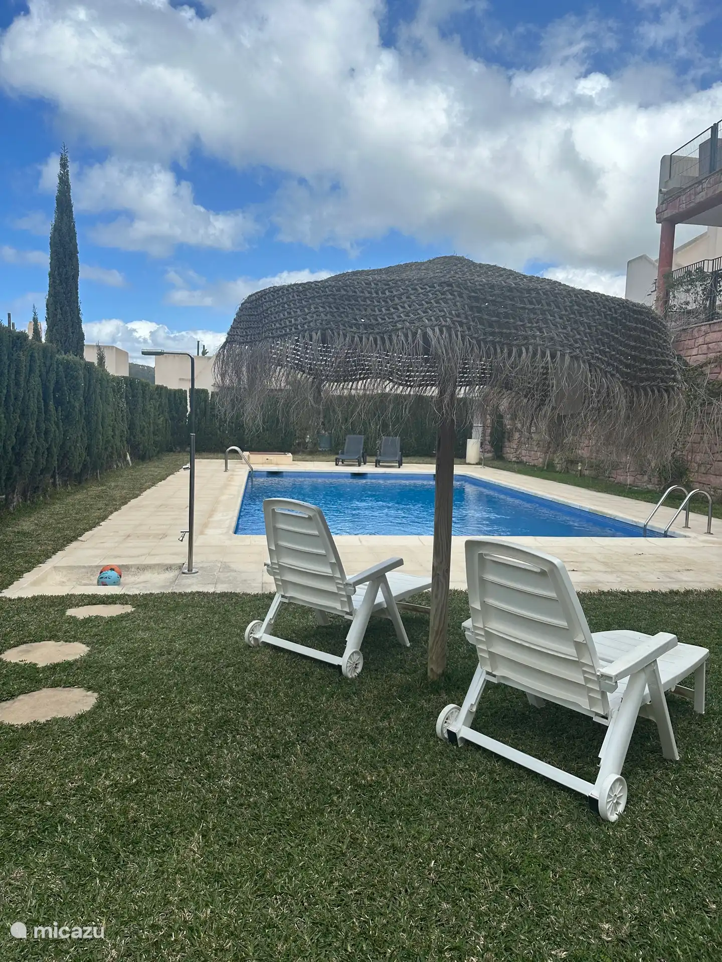 Zwembad met ligstoelen en douche