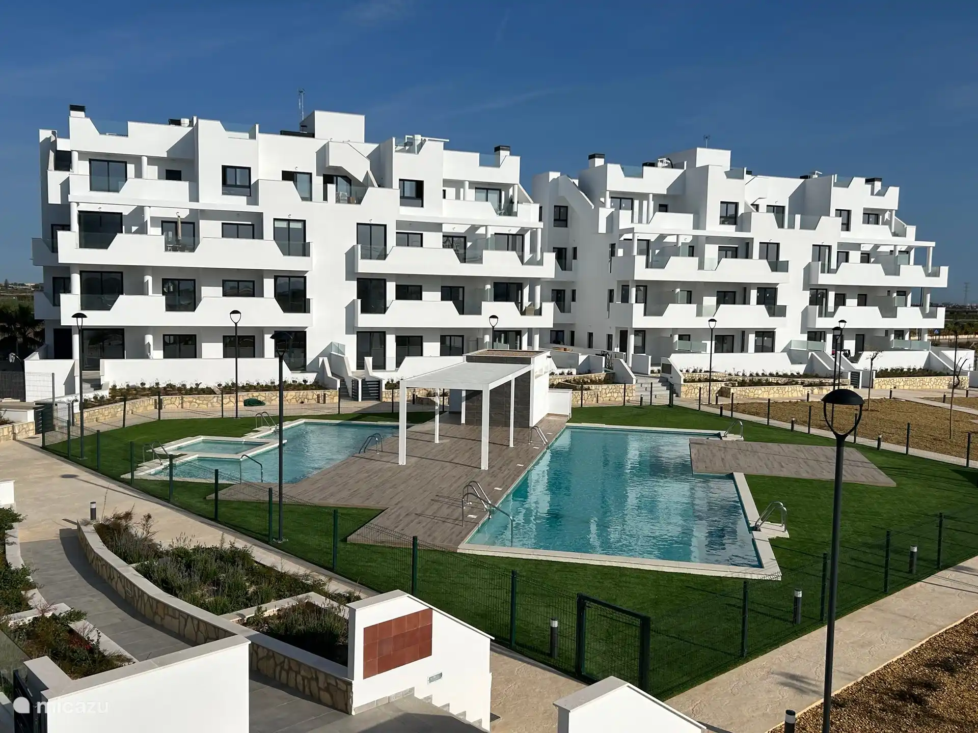 Vista a la piscina, al jardín y al parque infantil desde la terraza.