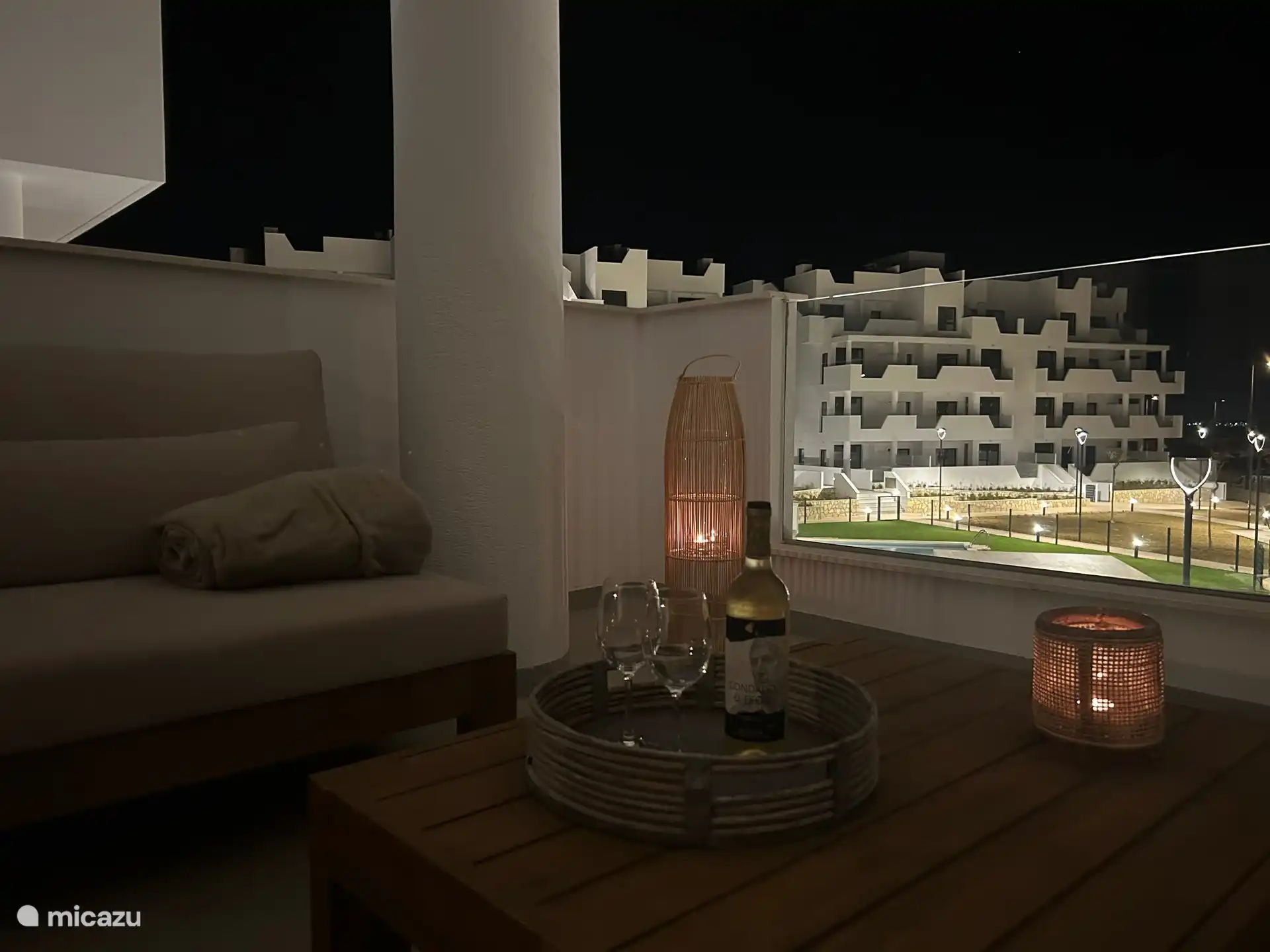 Acogedora terraza con vistas a la piscina y al jardín por la noche.