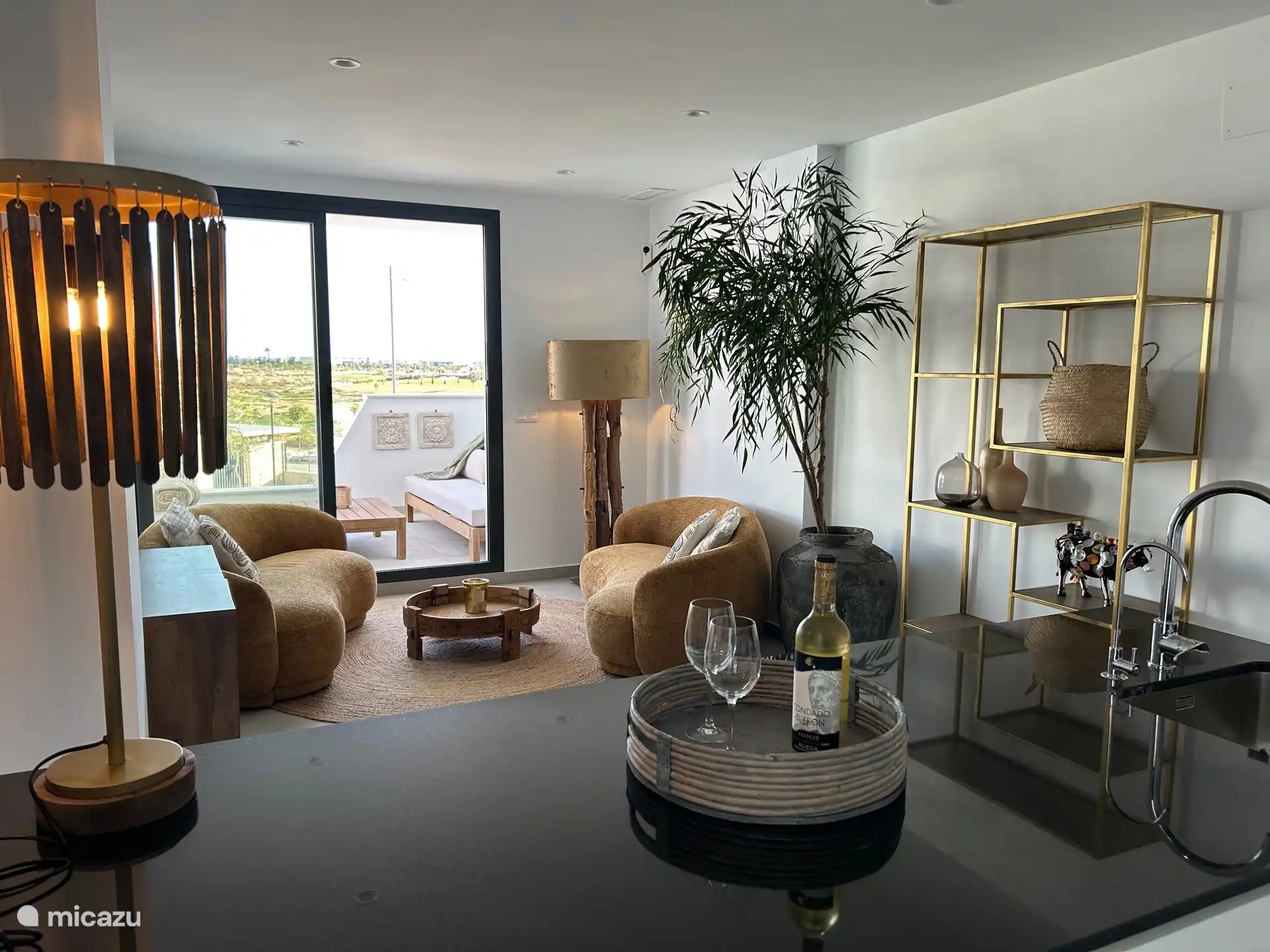 Salón comedor con cocina abierta e isla con acceso a la acogedora terraza del salón.