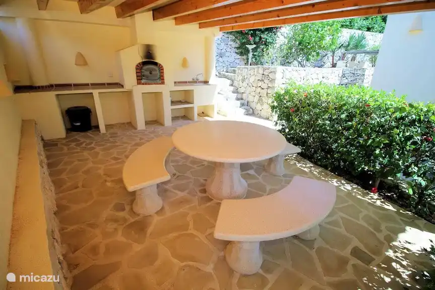 Überdachte Terrasse mit Pizzaofen und Natursteintisch und Bänken