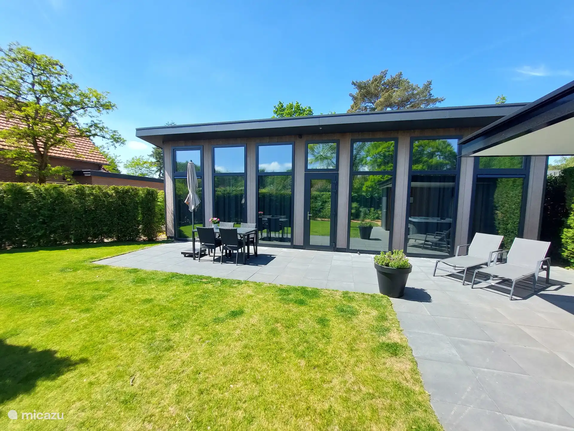 Ruime tuin met tuinset, ligbedden, parasol, jacuzzi en berging