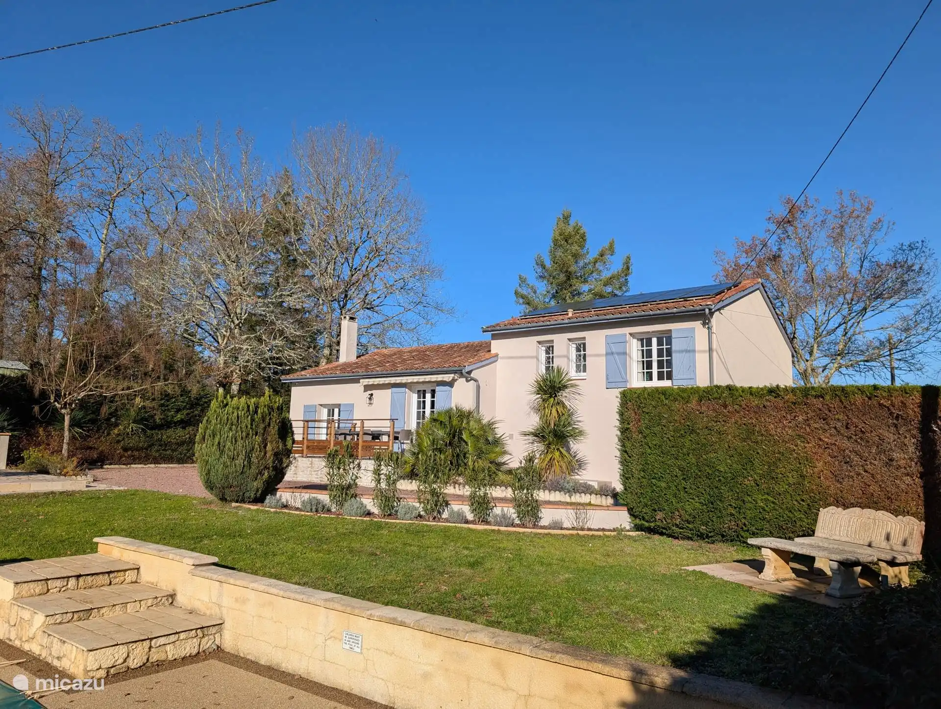 Achterzijde woning met terras en uitzicht op het zwembad en de tuin