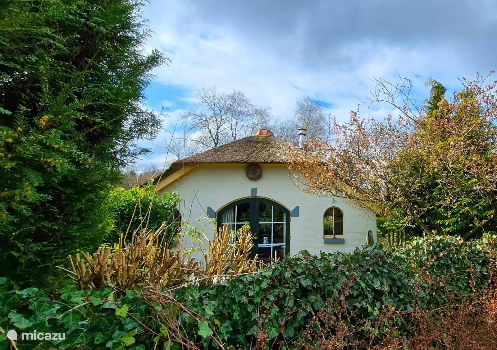 A spacious garden surrounds the cottage, with several seating areas