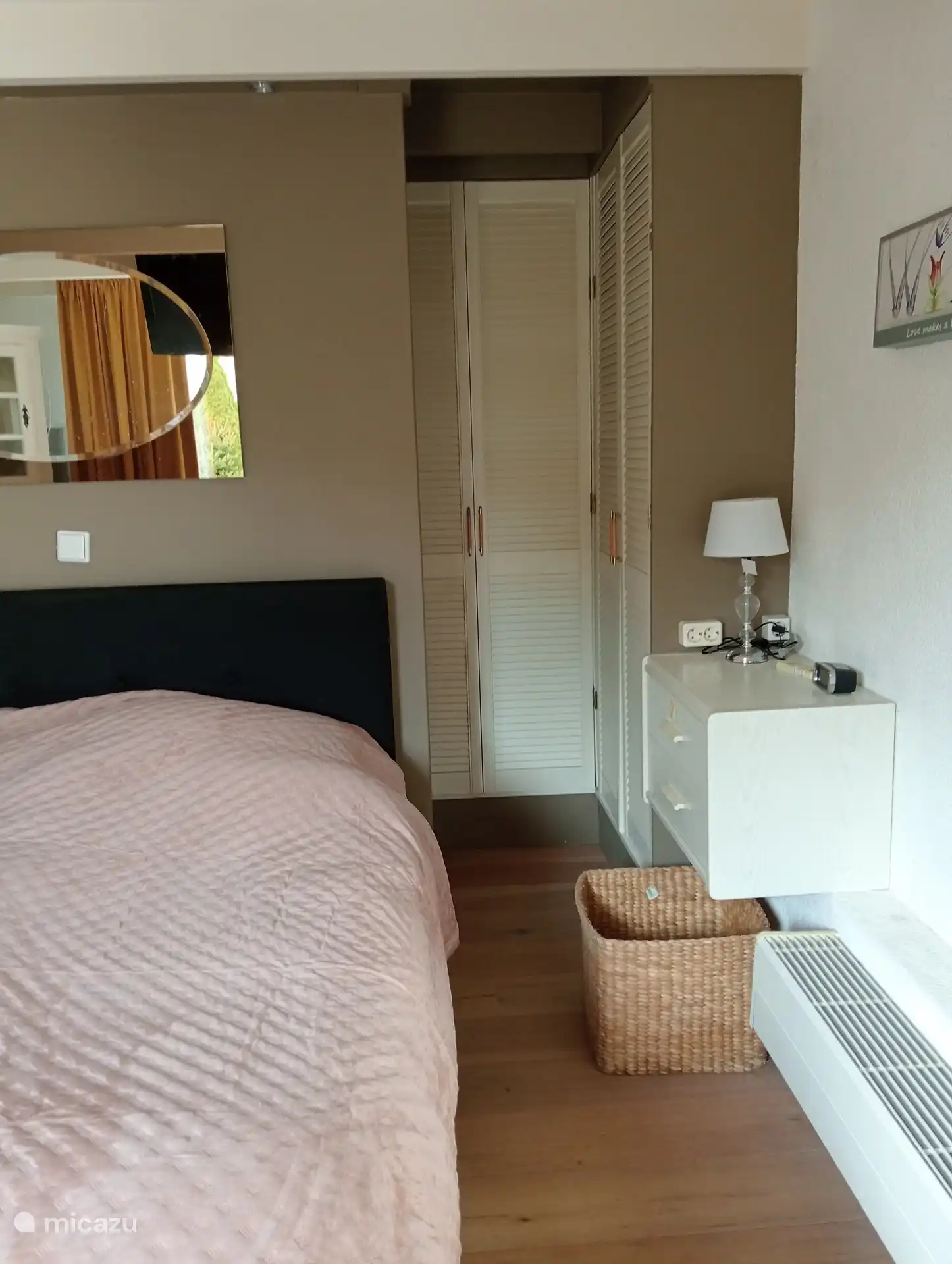 On both sides behind the bed is a spacious walk-in closet with hanging areas and practical storage space for clothes