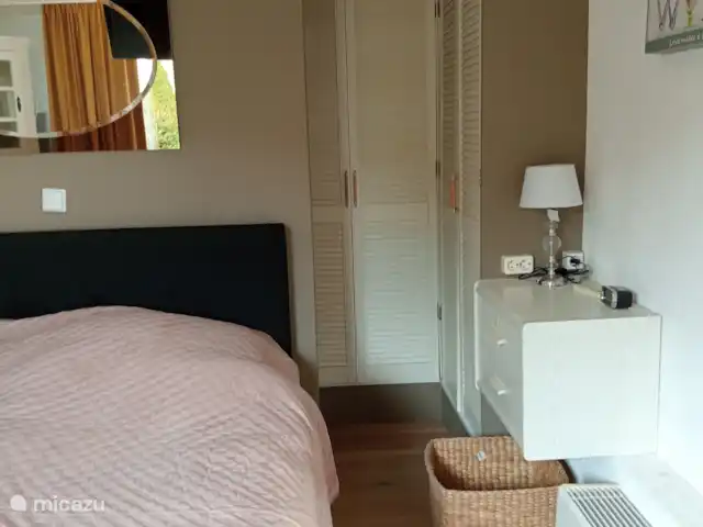 bungaló en Países Bajos, Güeldres, Putten – El lugar de Veluwe A ambos lados, detrás de la cama, hay un amplio vestidor con áreas para colgar y un práctico espacio de almacenamiento para la ropa