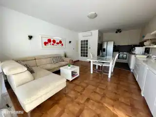 De woonkamer met open keuken. Een grote hoekbank.