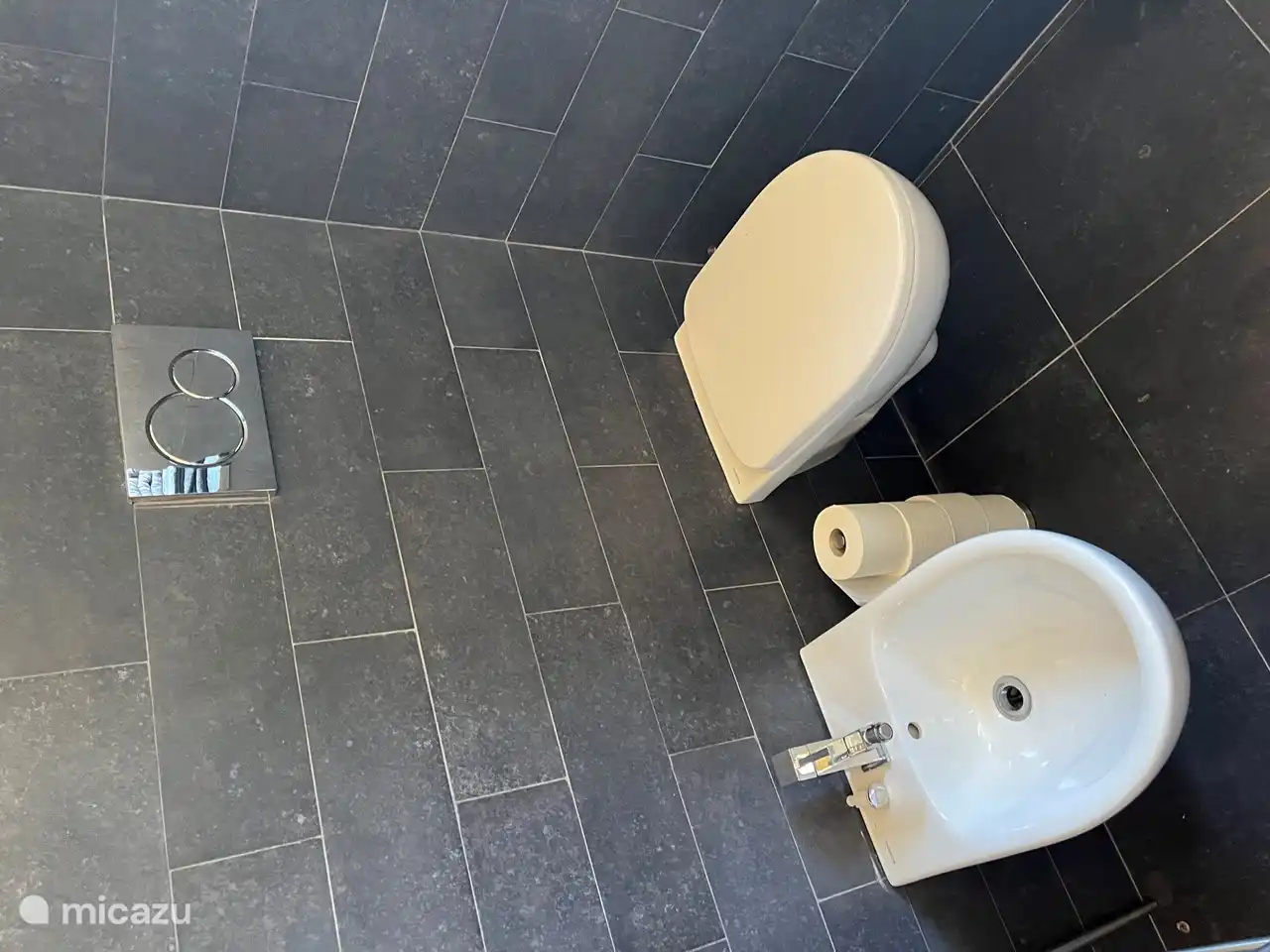 Badezimmer mit Bidet, Waschbecken, Toilette und beheiztem Spiegel.