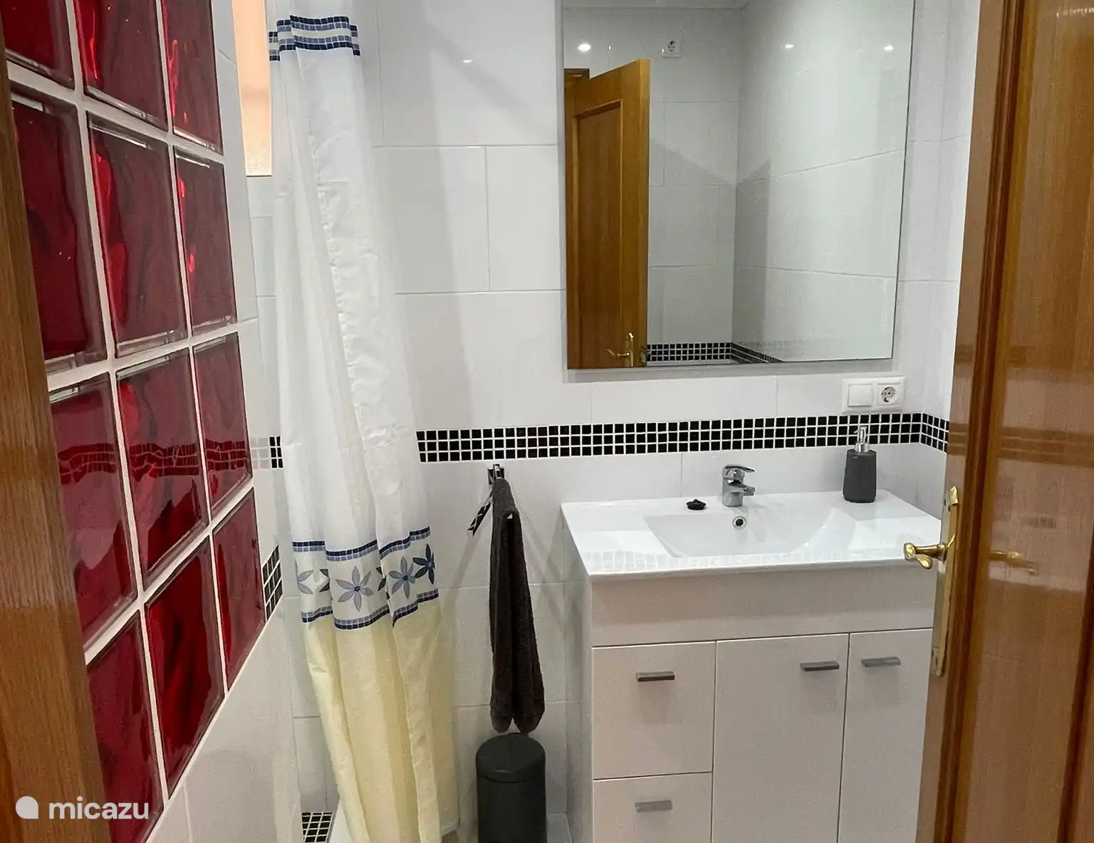 Das Badezimmer verfügt über ein Waschbecken, eine Toilette und eine ebenerdige Dusche mit Regendusche und Handbrause.