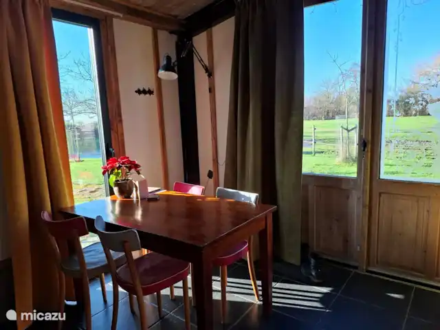 Le doux Ermgaard  | Pays-Bas, Zélande, Oudelande - maison mitoyenne Table à manger dans le salon avec beaucoup de lumière et vue sur la prairie.