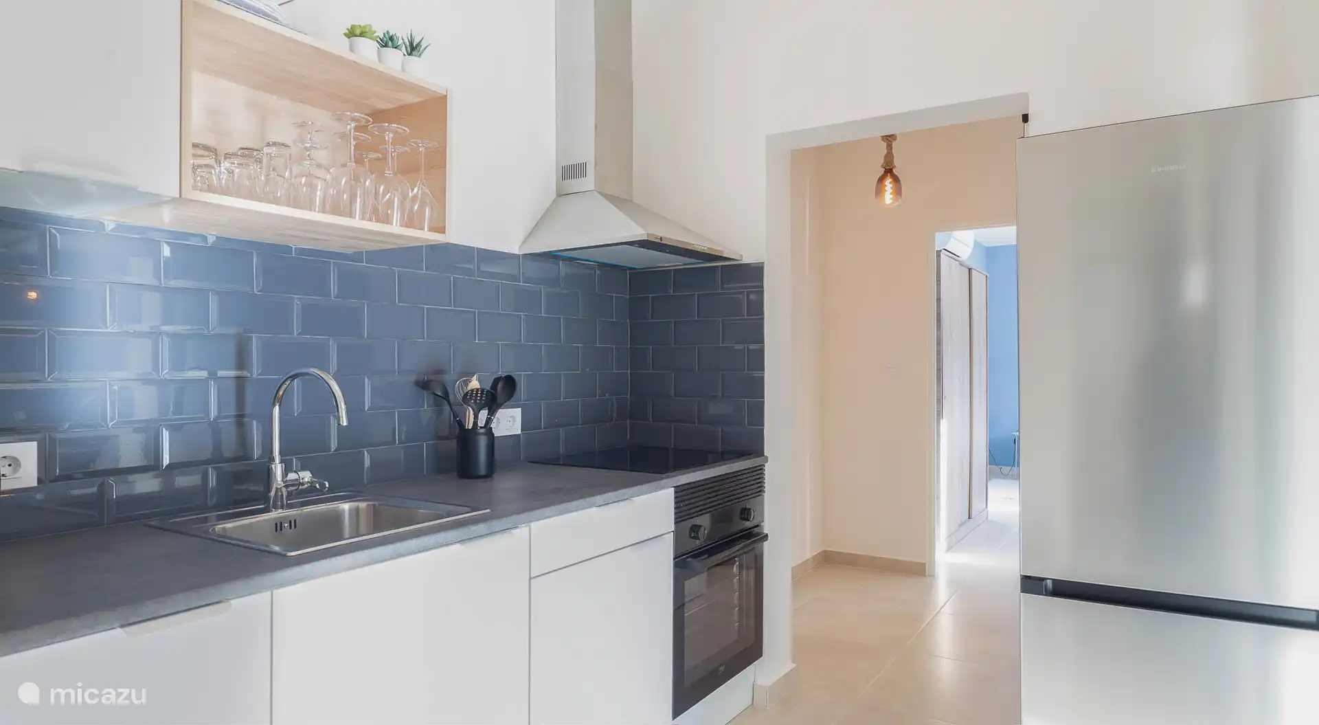 La cuisine dispose d’une plaque à induction, d’un four et d’un réfrigérateur séparé avec compartiment congélateur