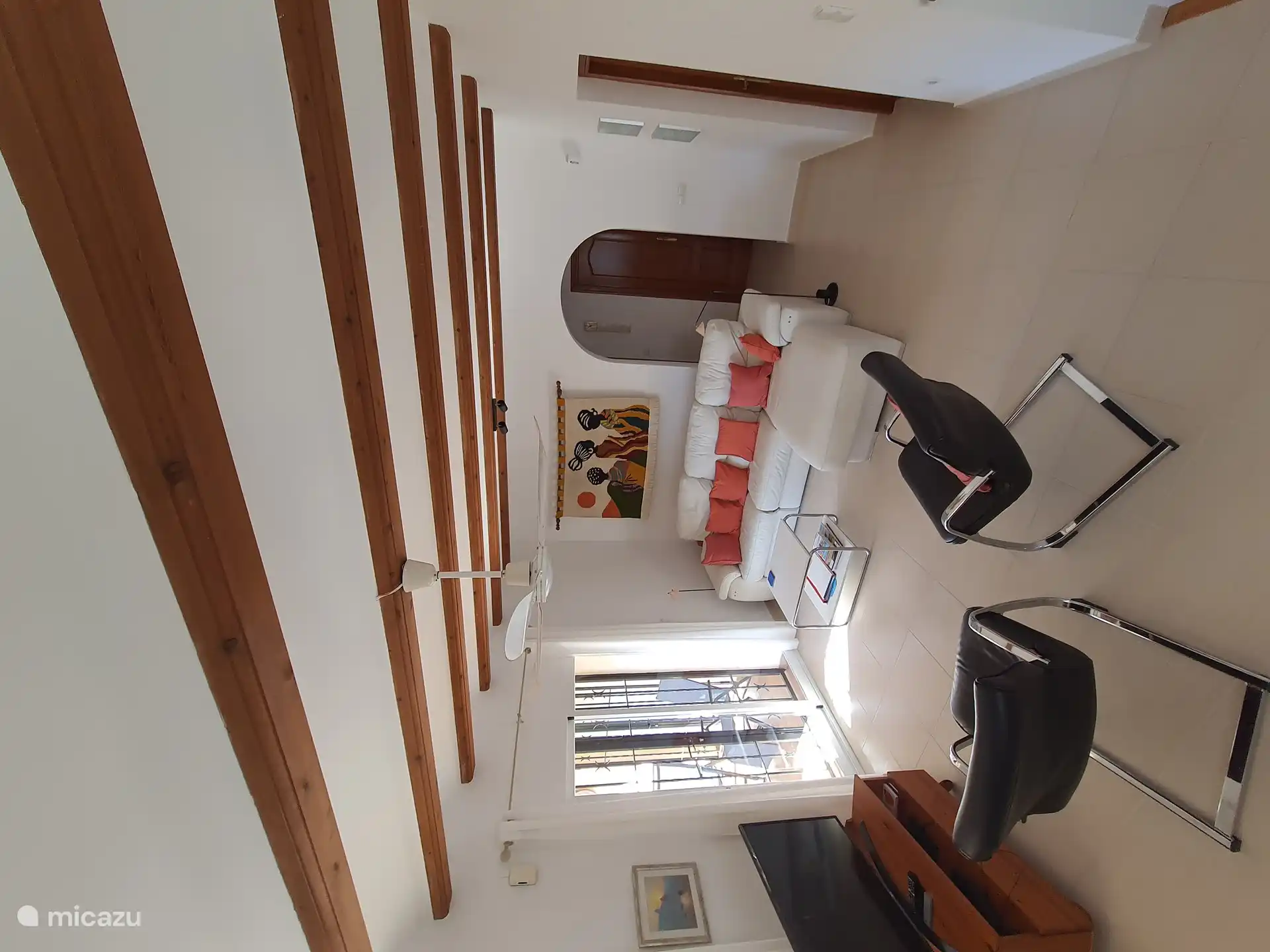 Wohnzimmer mit Sofa, mehreren Sesseln und Türen zur Terrasse im Obergeschoss