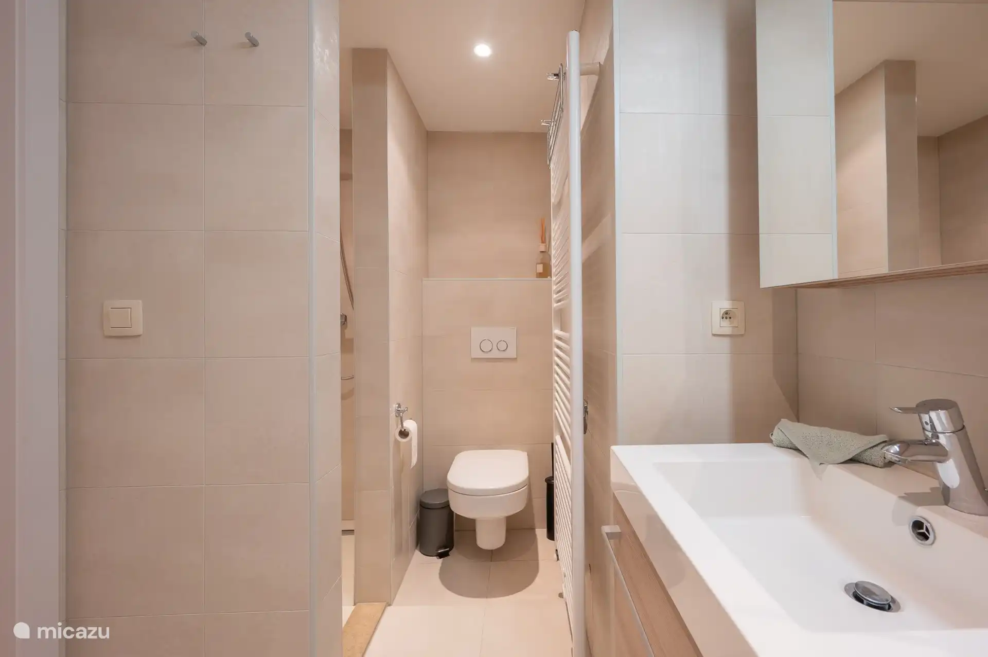 Badezimmer mit WC, Dusche, Handtuchtrockner, Doppelwaschbecken, WC-Schrank und Badewanne