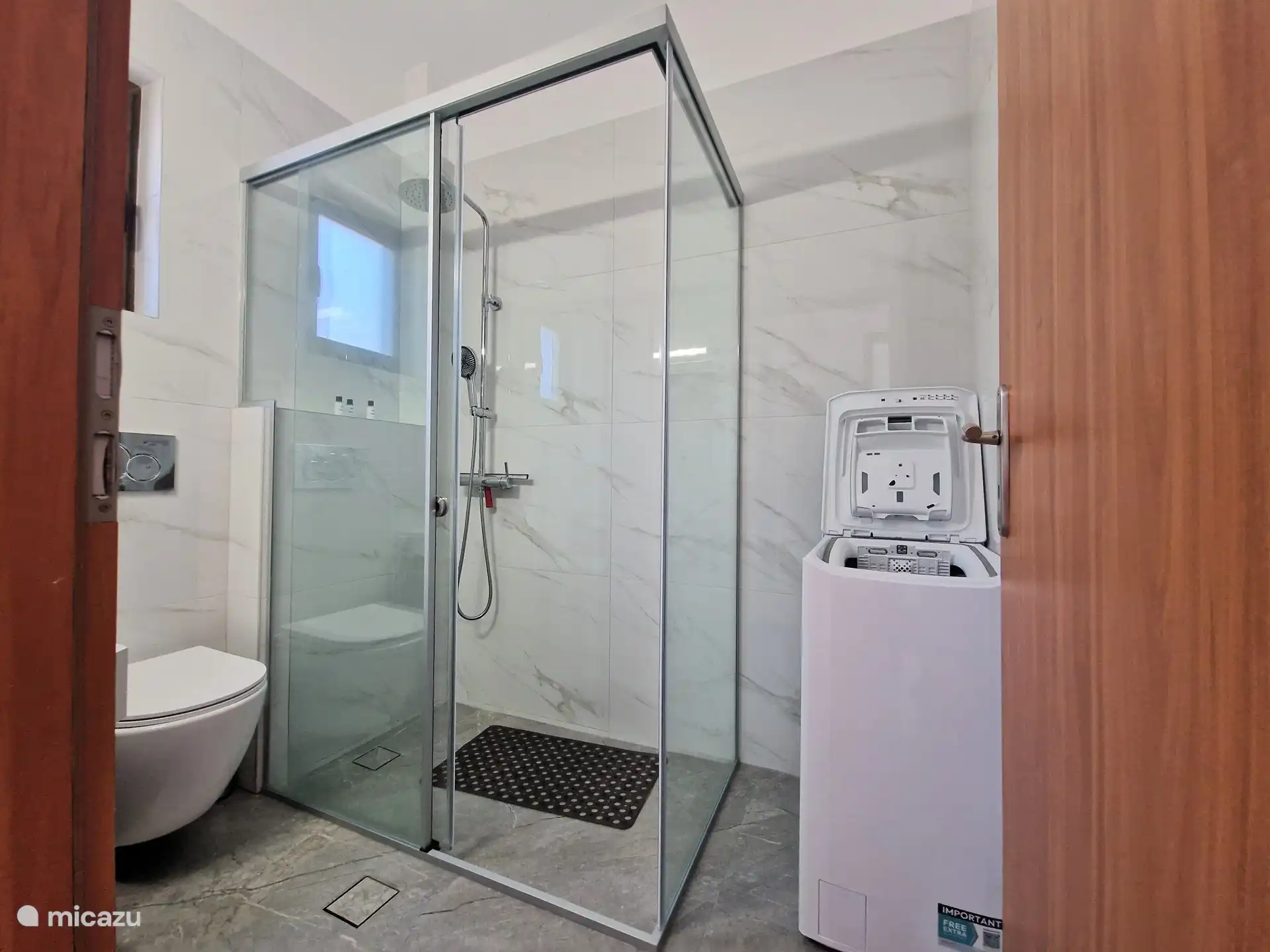 De badkamer met wasmachine en inloopdouche