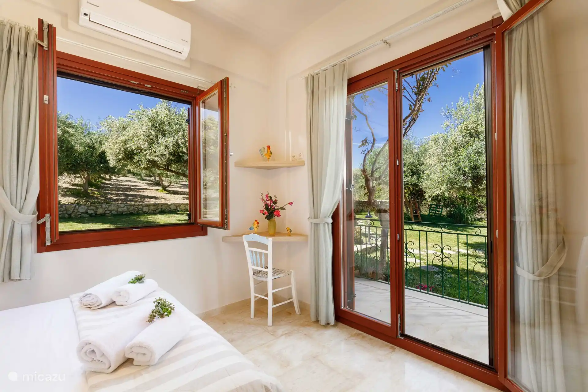 Das westliche Schlafzimmer mit einem Doppelbett mit Blick auf den Garten mit den Olivenbäumen 