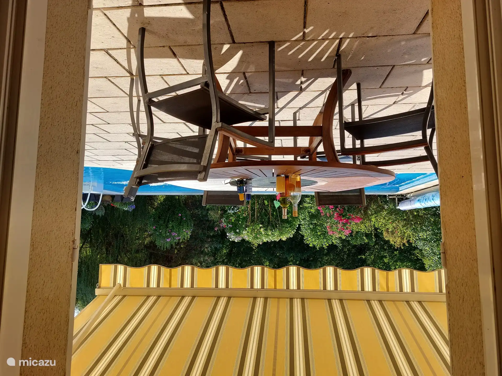 Blick vom Wohnzimmer auf die Terrasse, den Pool und den Garten. Sonnenschutz und Fensterläden vorhanden.