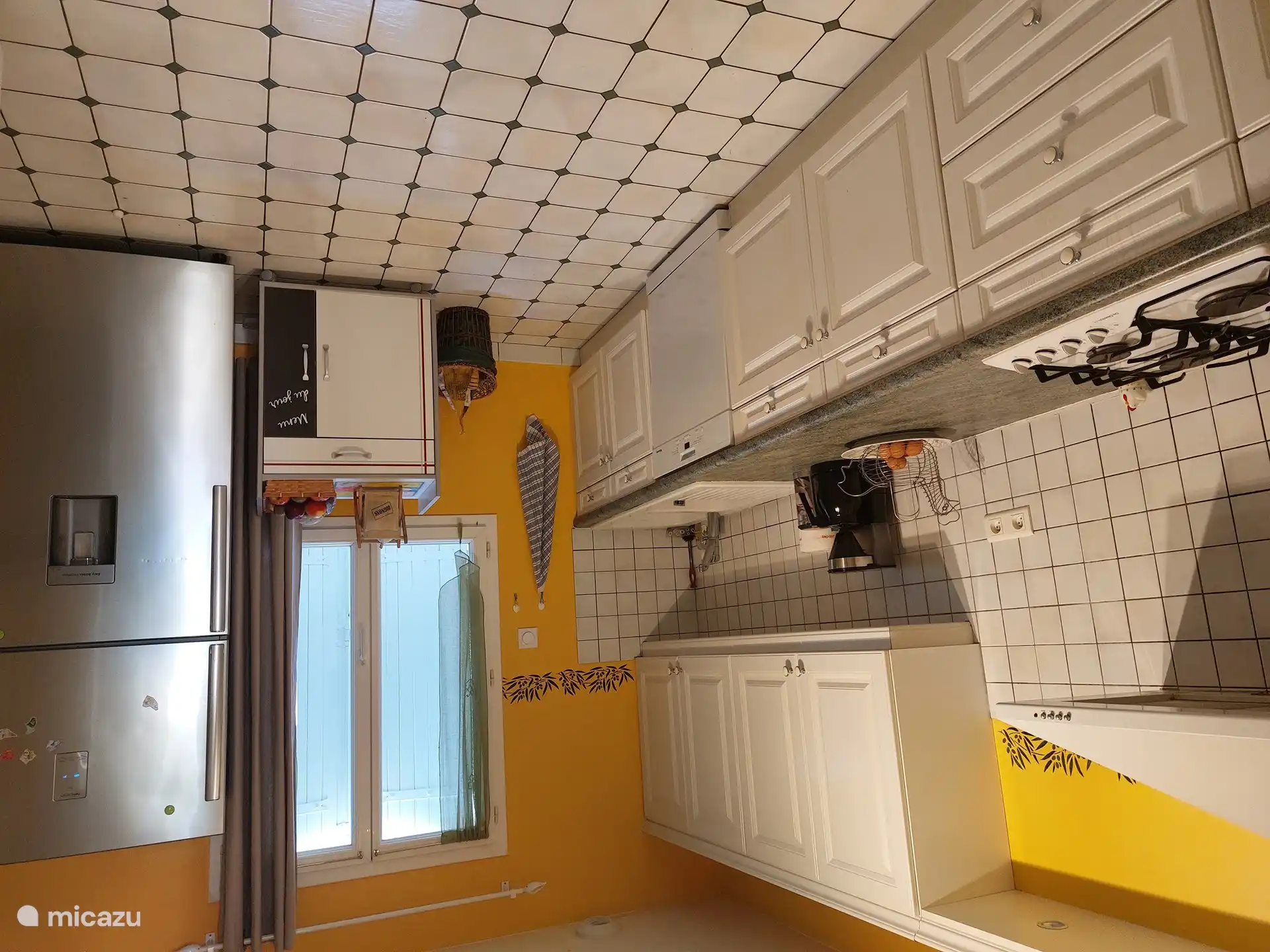 Küche mit Kühlschrank mit Gefrierfach, Gasherd, Mikrowelle, Backofen, Kaffeemaschine und Heißwassergerät.