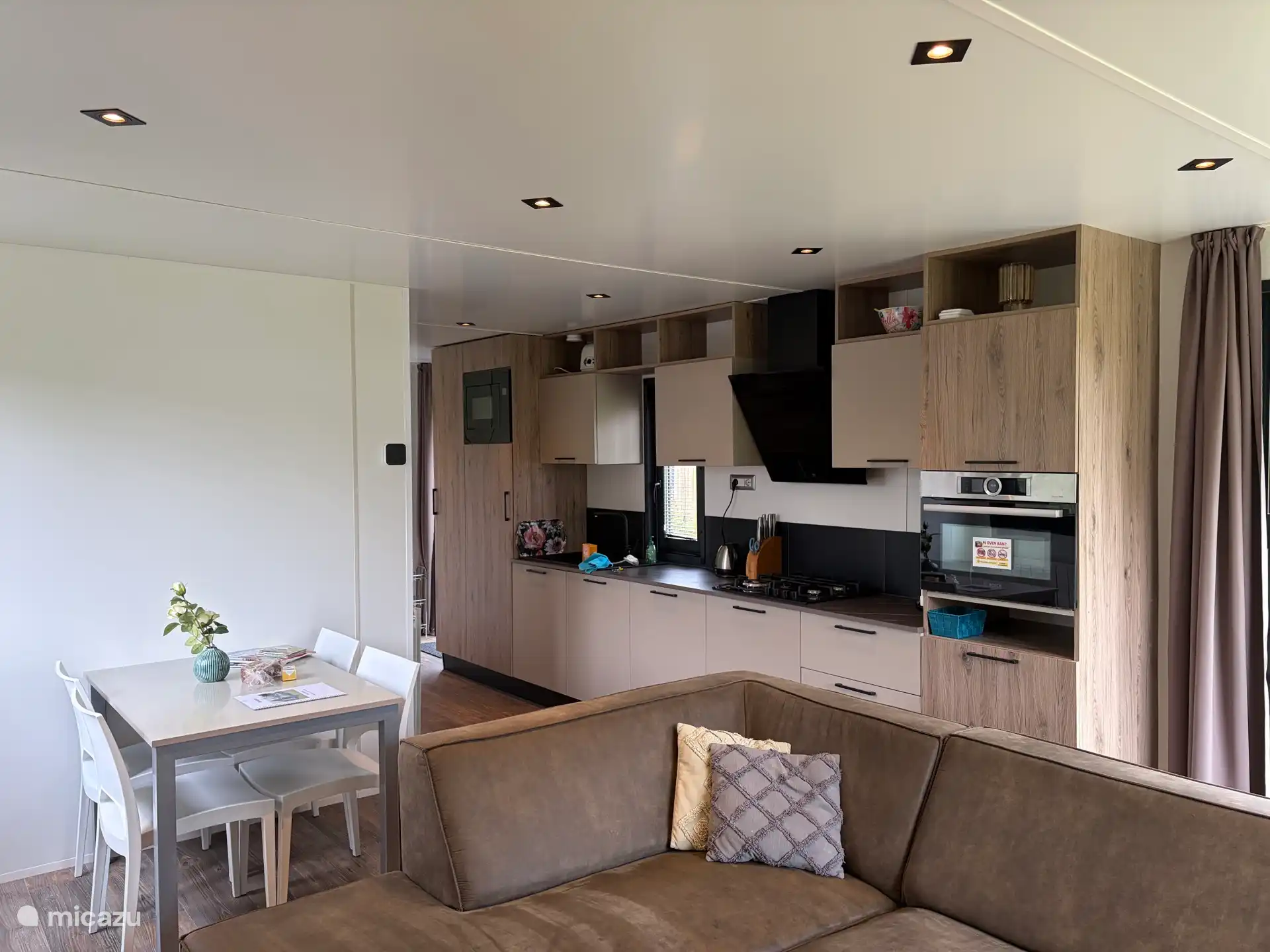 The living room has a spacious corner sofa and dining room table with four chairs. In addition, there is also a baby chair available.