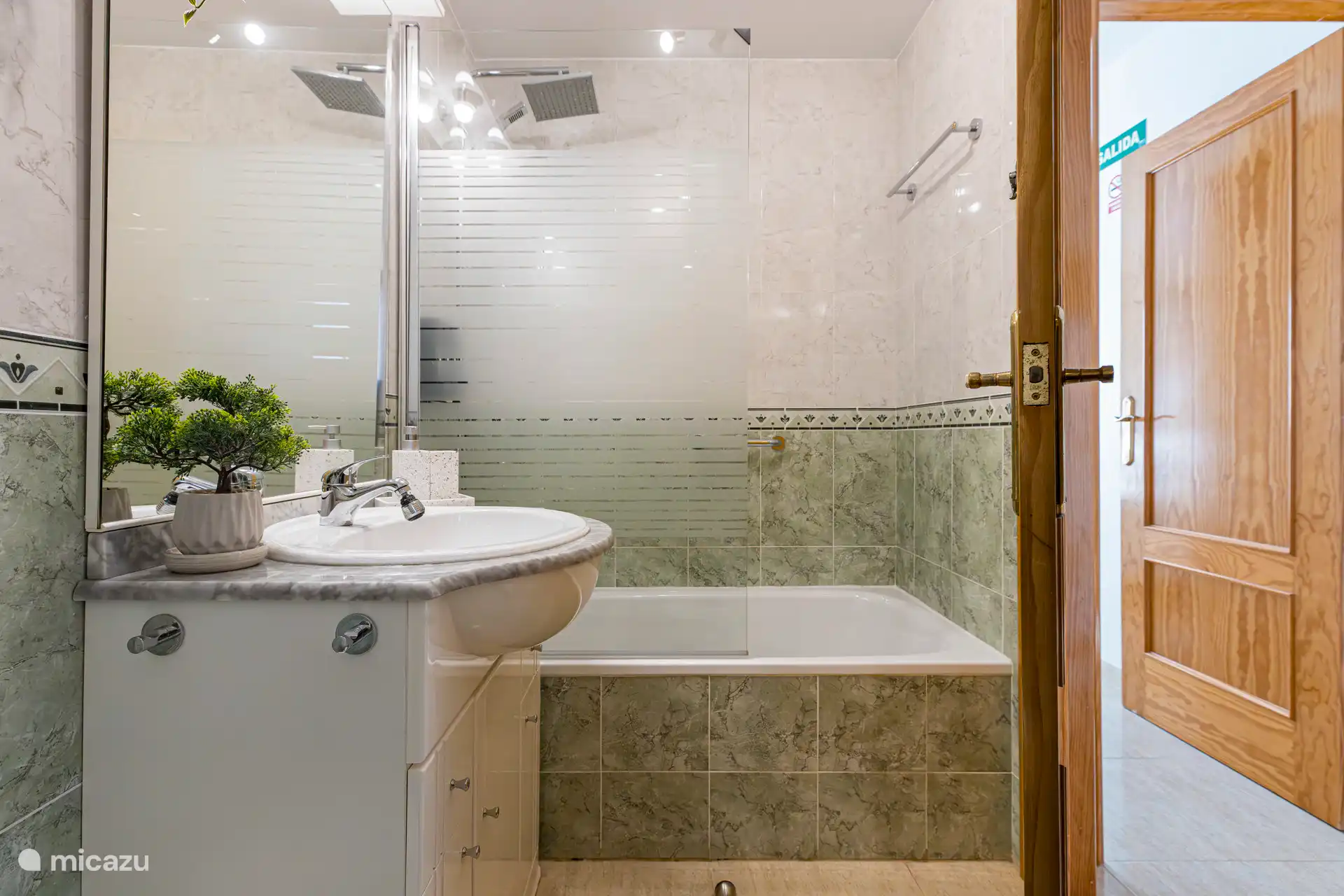 Salle de bain complète avec baignoire et douche, bar d’appui dans la baignoire.