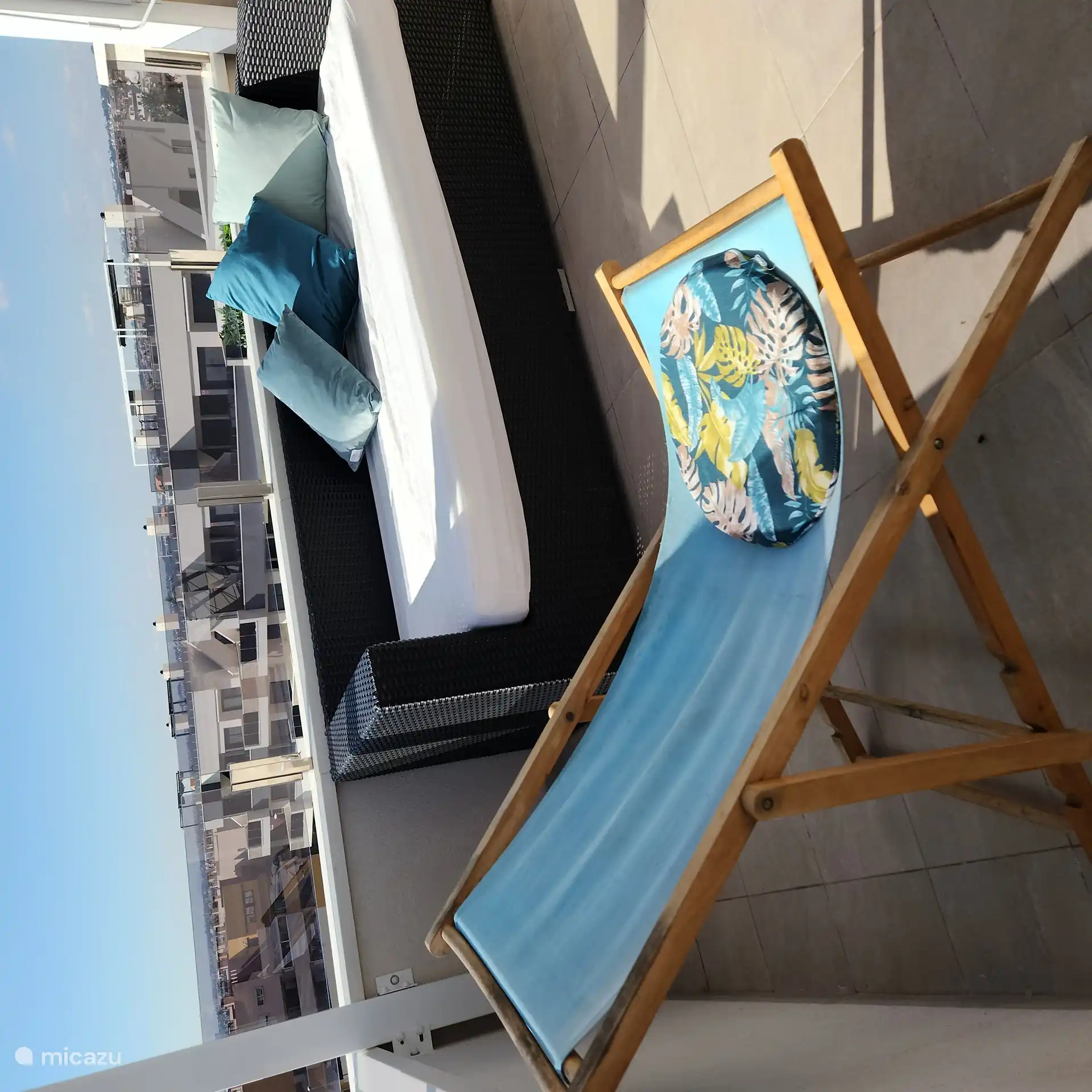 Terrasse sur le toit avec des chaises, des brancards, une chaise suspendue et un canapé avec un matelas ferme