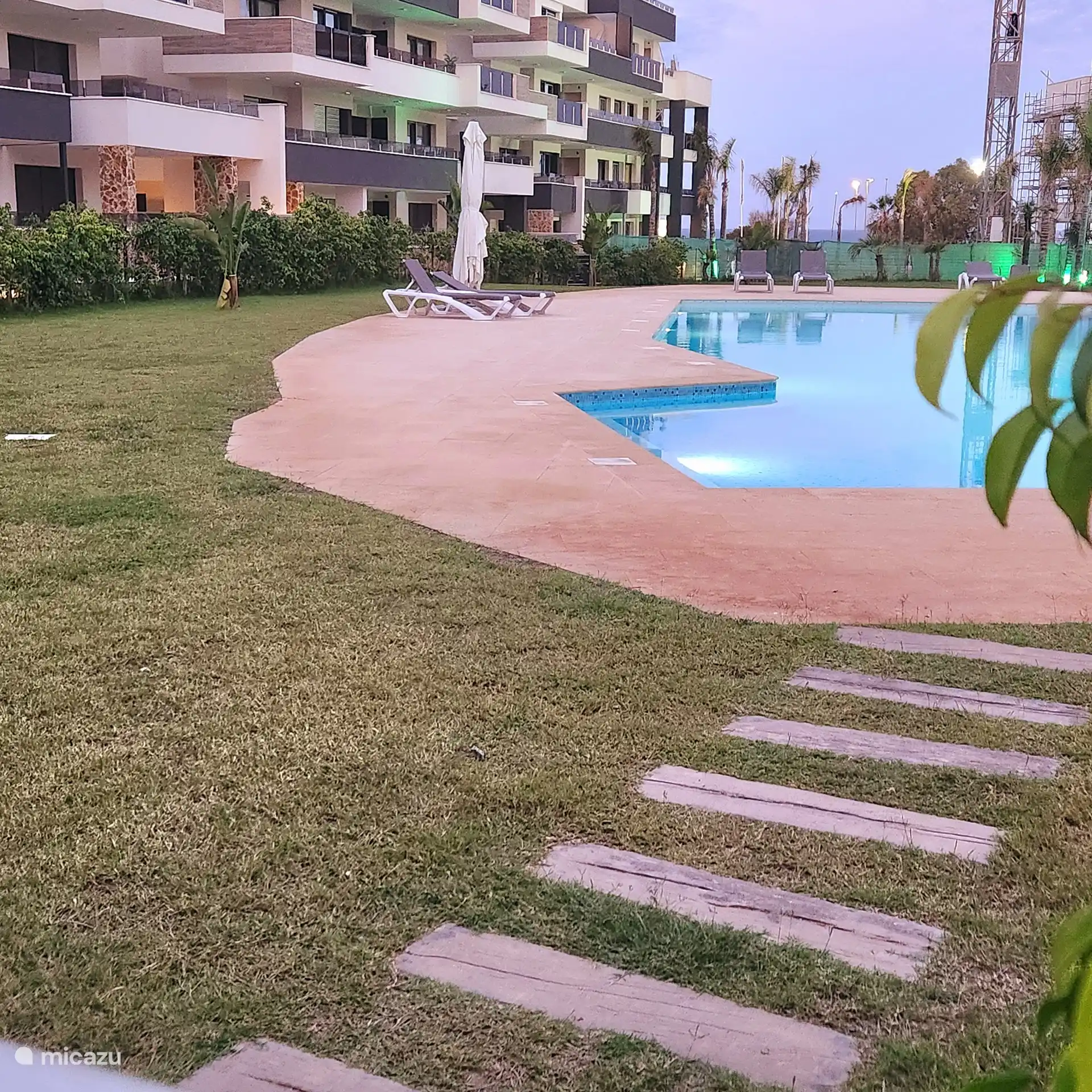Piscine commune avec escaliers intégrés, chaises longues et parasols 