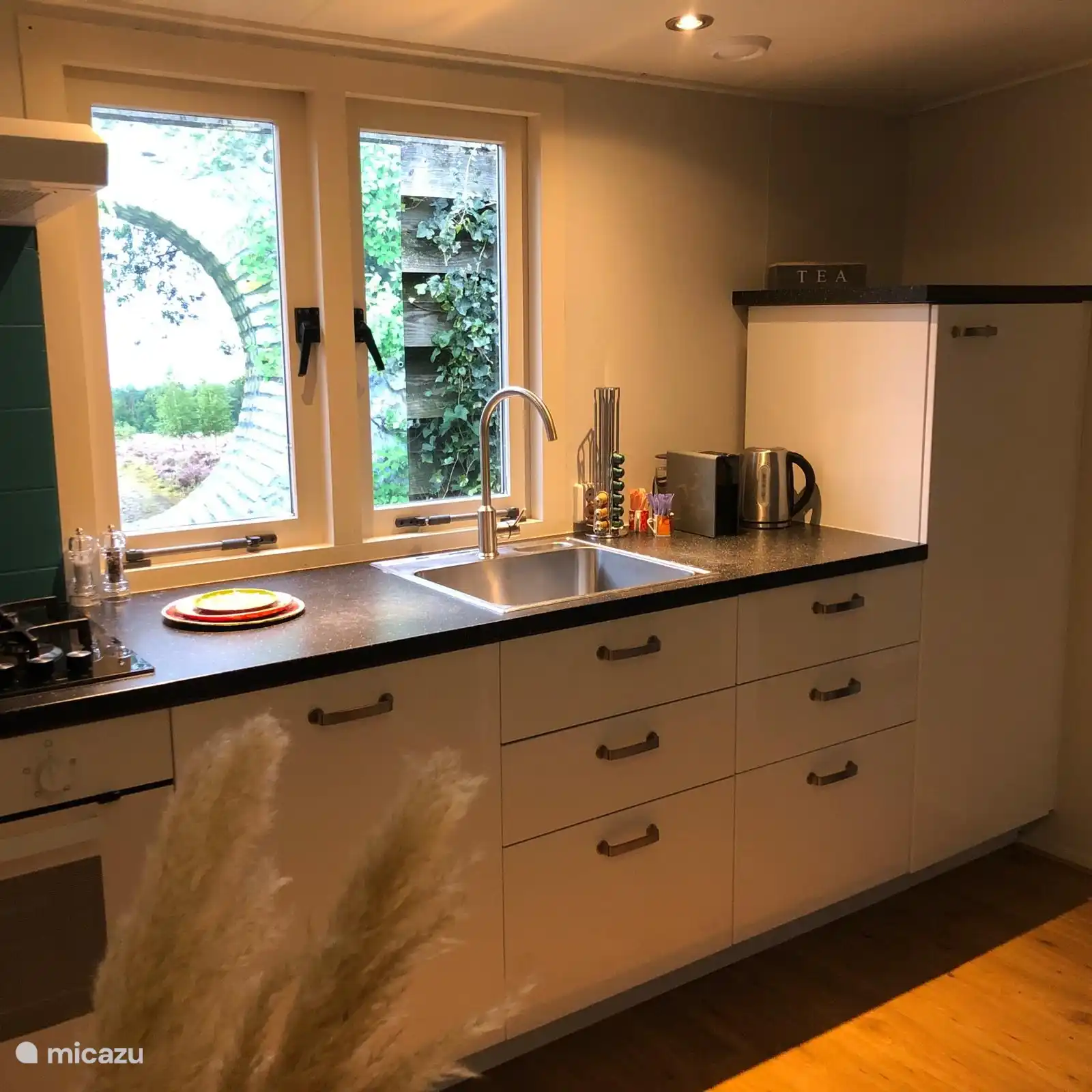 Cuisine avec four, cafetière et bouilloire.