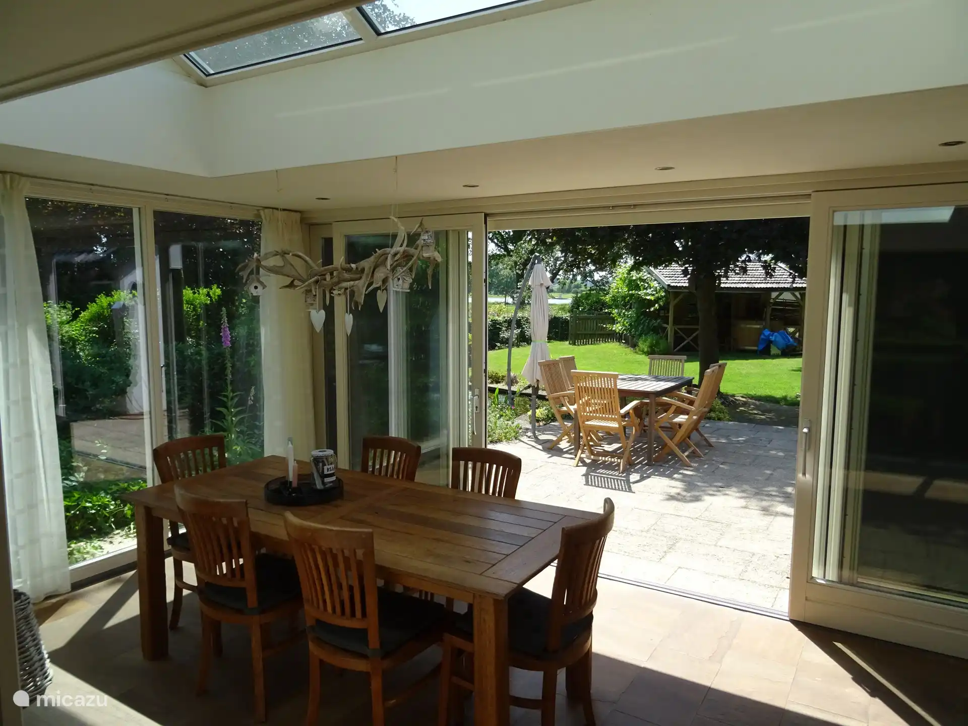 Geräumiger Wintergarten mit Zugang zum Garten. Vom Wintergarten aus kann man die vorbeifahrenden Boote sehen.