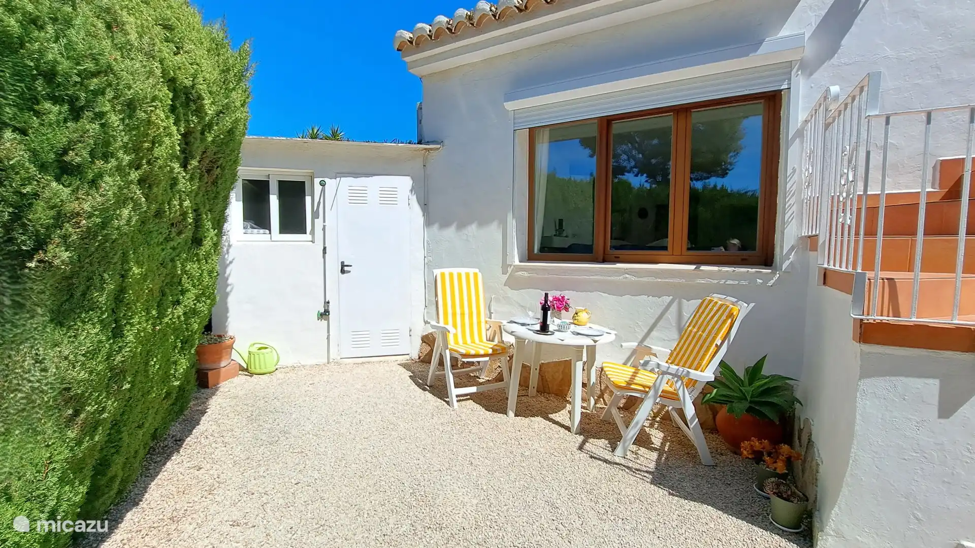 Terraza en el lateral de la casa y entrada al gran granero donde se pueden aparcar una o más bicicletas. 