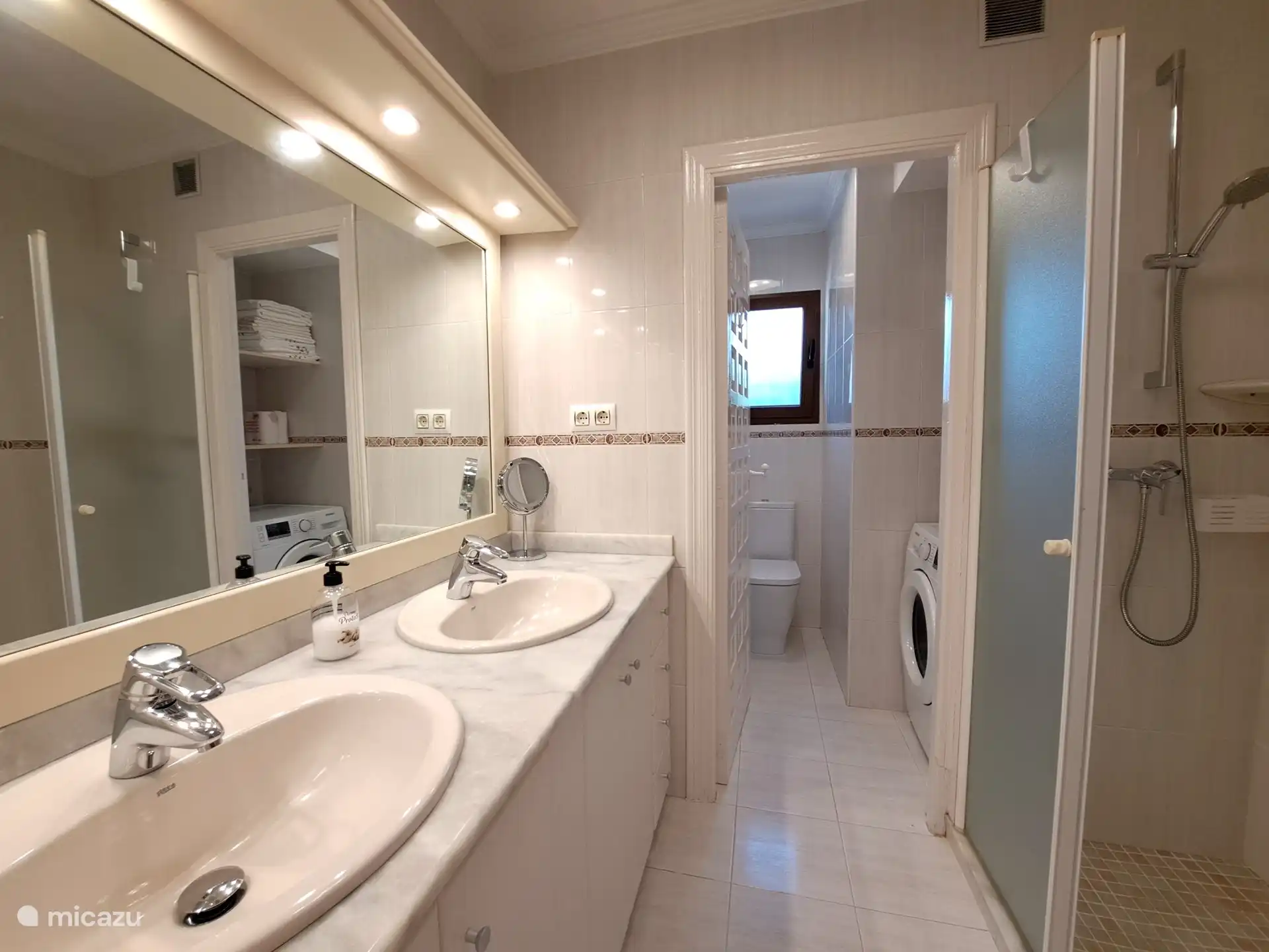 La salle de bain spacieuse avec douche à l’italienne, toilettes séparées, machine à laver et de nombreux rangements.