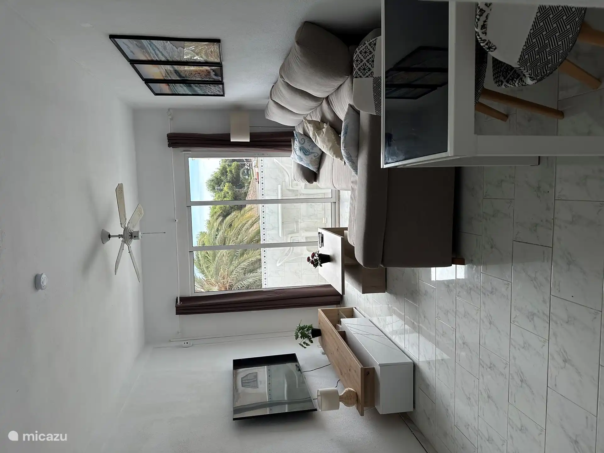 Sala de estar con TV grande, sofá salón y puerta corredera al balcón orientado al sur 