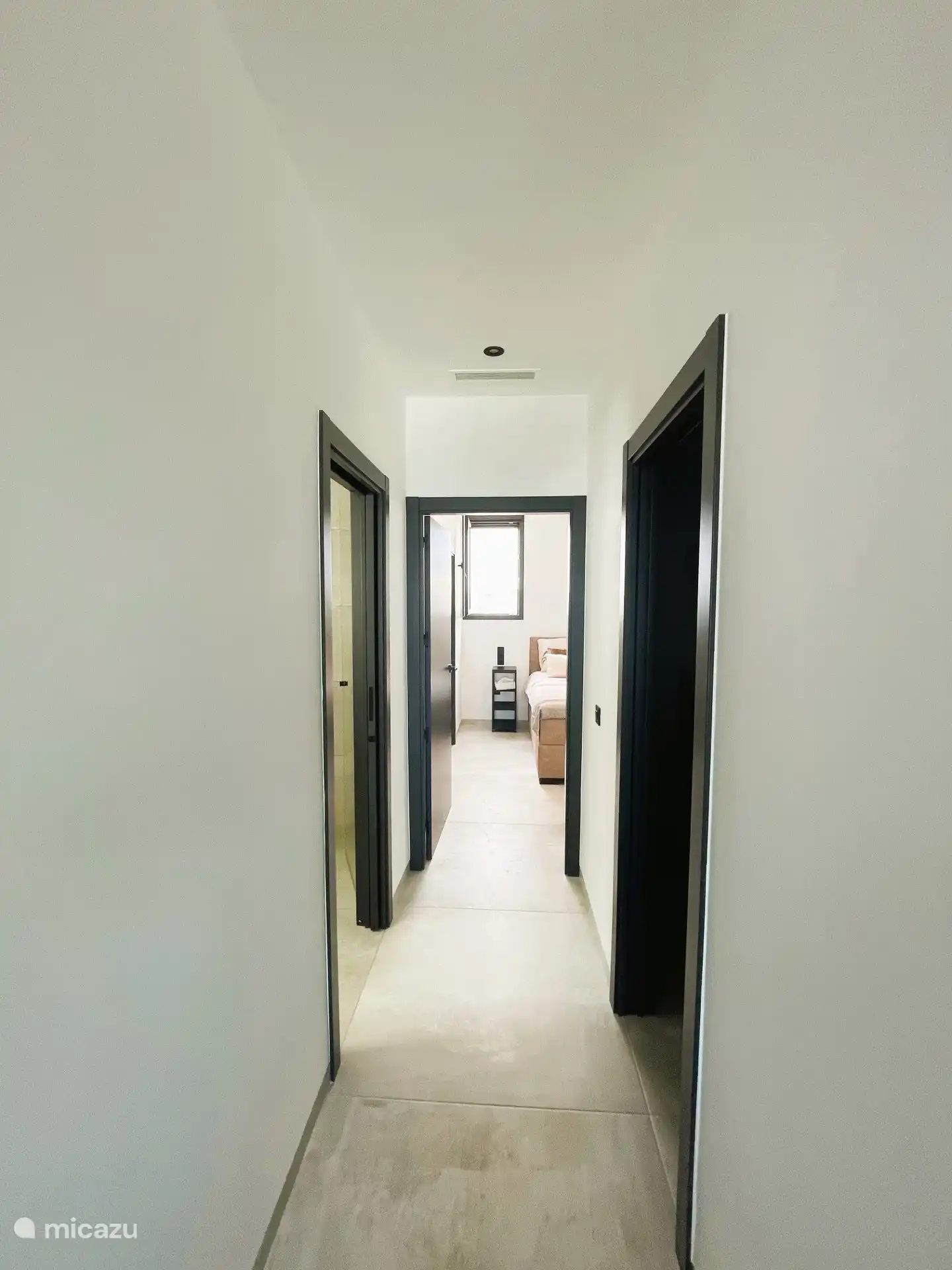 The hallway with a bedroom on the right, a bathroom on the left and the ensuite bedroom in the back with a private bathroom