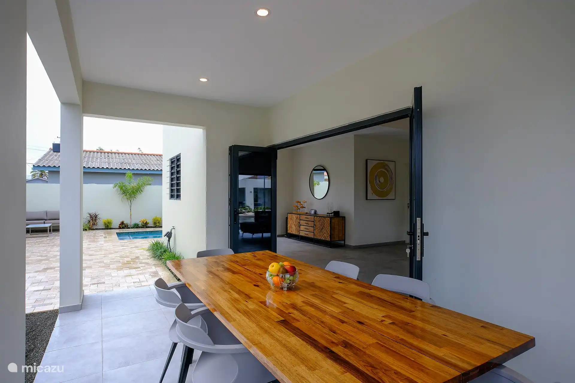 Table en bois spacieuse pour 6 personnes avec chaises modernes donnant sur la piscine