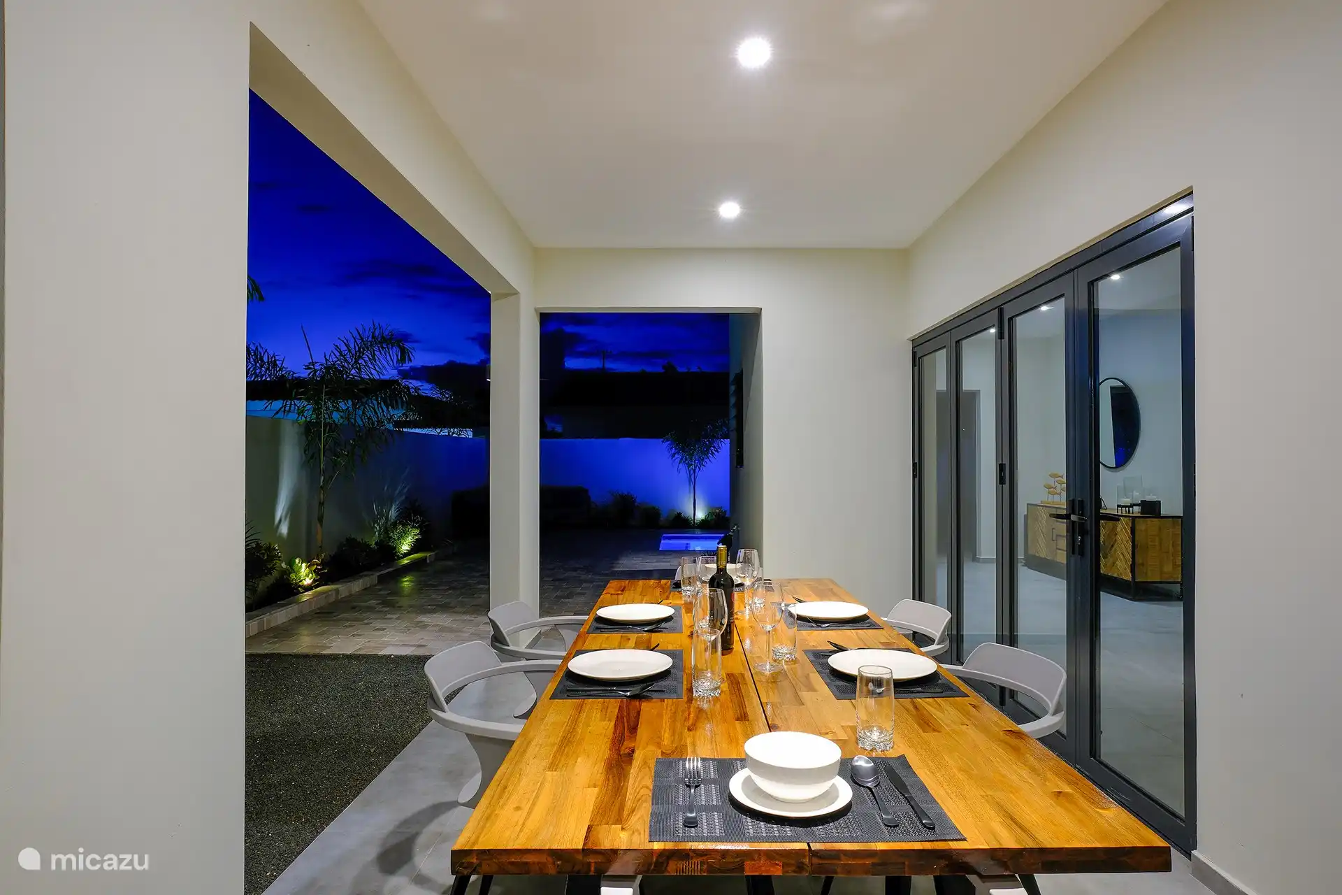 Table en bois spacieuse pour 6 personnes avec chaises modernes donnant sur la piscine