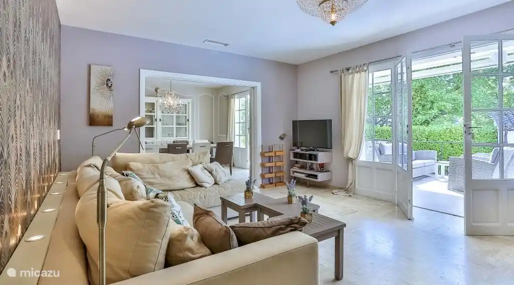Living room with a view of a lovely terrace with dining table.