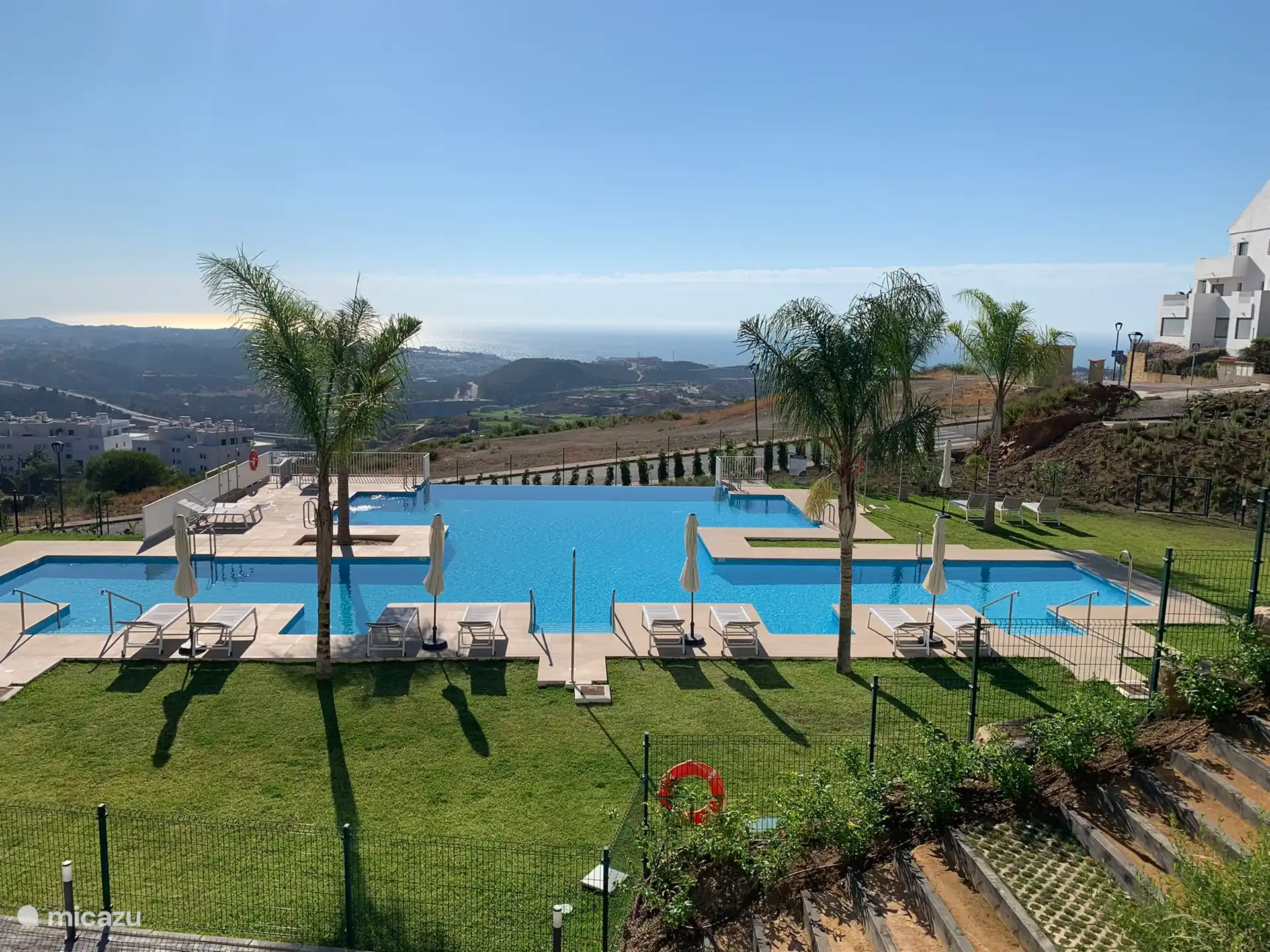 Großer Außenpool mit Liegestühlen und Sonnenschirmen in einem angelegten Garten