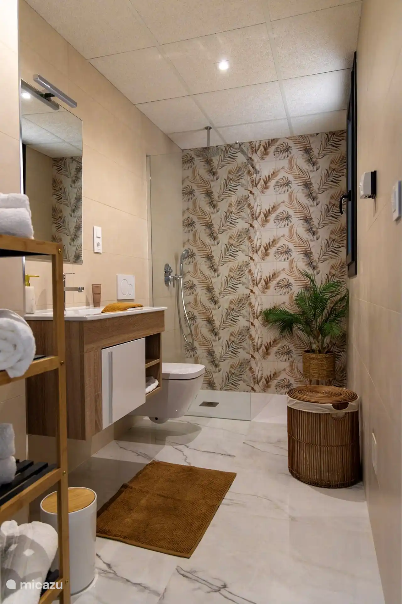 Un amplio cuarto de baño independiente con ducha de efecto lluvia, una ducha de mano separada para mayor comodidad, un lavabo de lujo y un inodoro colgante.