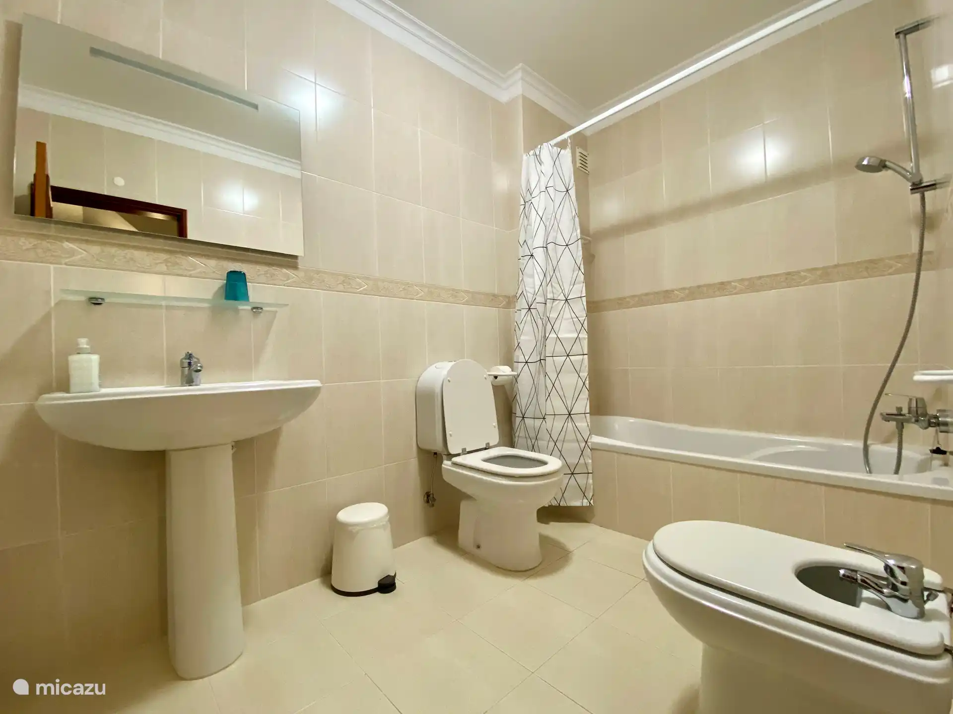 Geräumiges Badezimmer mit Badewanne, Dusche, Waschbecken mit beleuchtetem Spiegel, Bidet und WC.