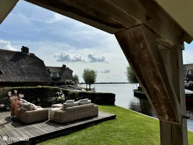 Villa Puur Giethoorn huren in Nederland, Overijssel, Wanneperveen - vakantiehuis Naast de lounge tref je links om het hoekje bij de openslaande deuren een tuintafel aan met goed zittende tuinstoelen. Je zit niet direct aan het water waardoor je niet volop in de wind zit maar wel zicht op het meer.