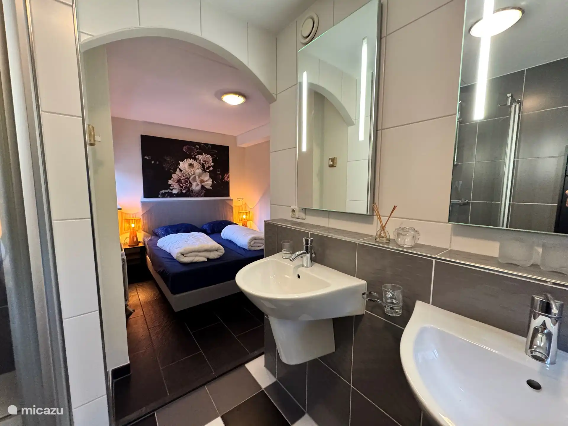 Im Erdgeschoss befindet sich ein Doppelzimmer mit Boxspringbett und ein geräumiges Badezimmer mit Doppelwaschbecken und begehbarer Dusche