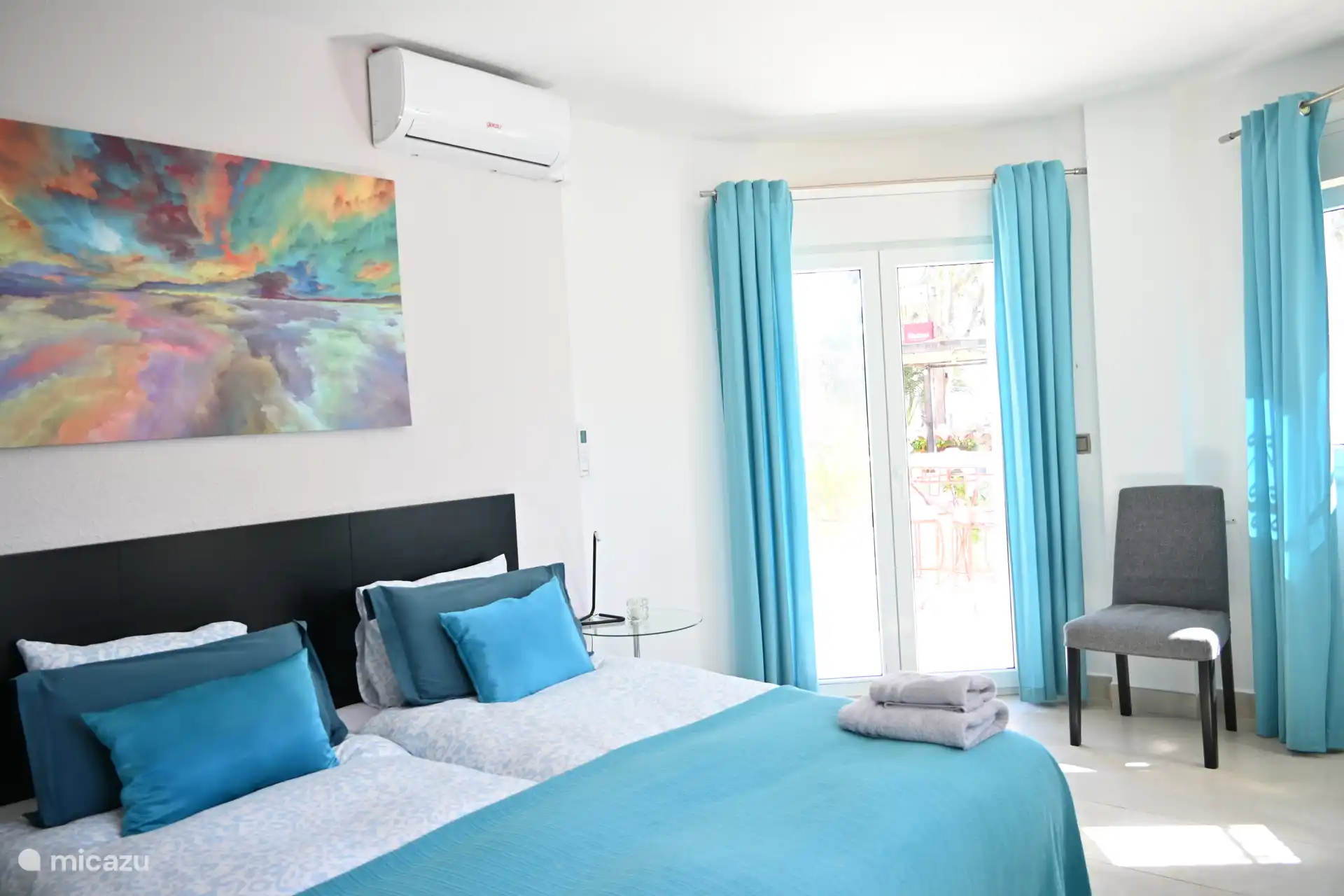 Dormitorio azul con puertas de patio que dan a la terraza con vistas al mar