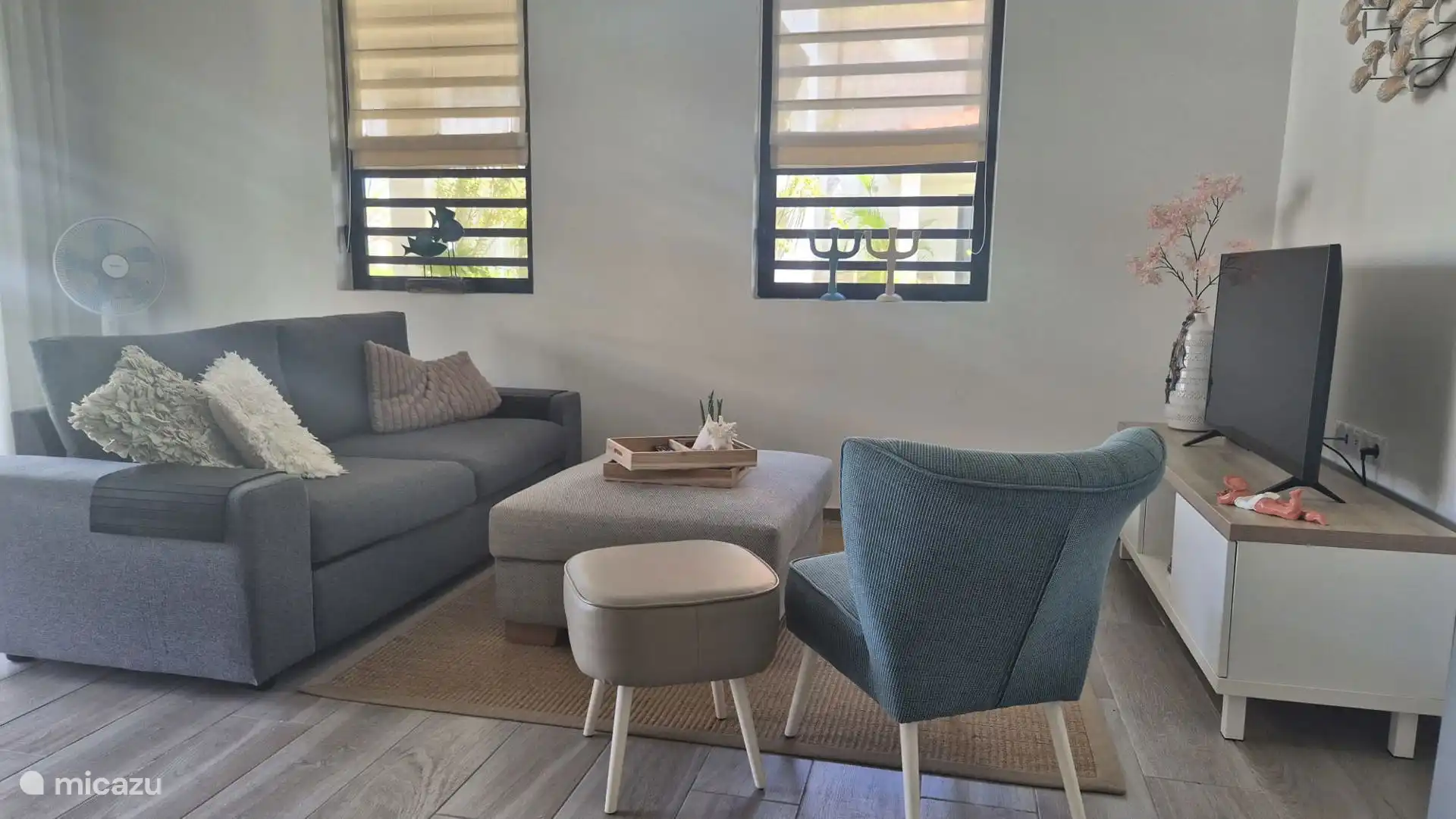 Wunderbar helles Wohnzimmer mit einem bequemen Sofa für zwei Personen und einem separaten Stuhl. Entspannen Sie sich vor dem Smart-TV und genießen Sie dank der praktischen Moskitonetze an den Fenstern einen mückenfreien Bereich!