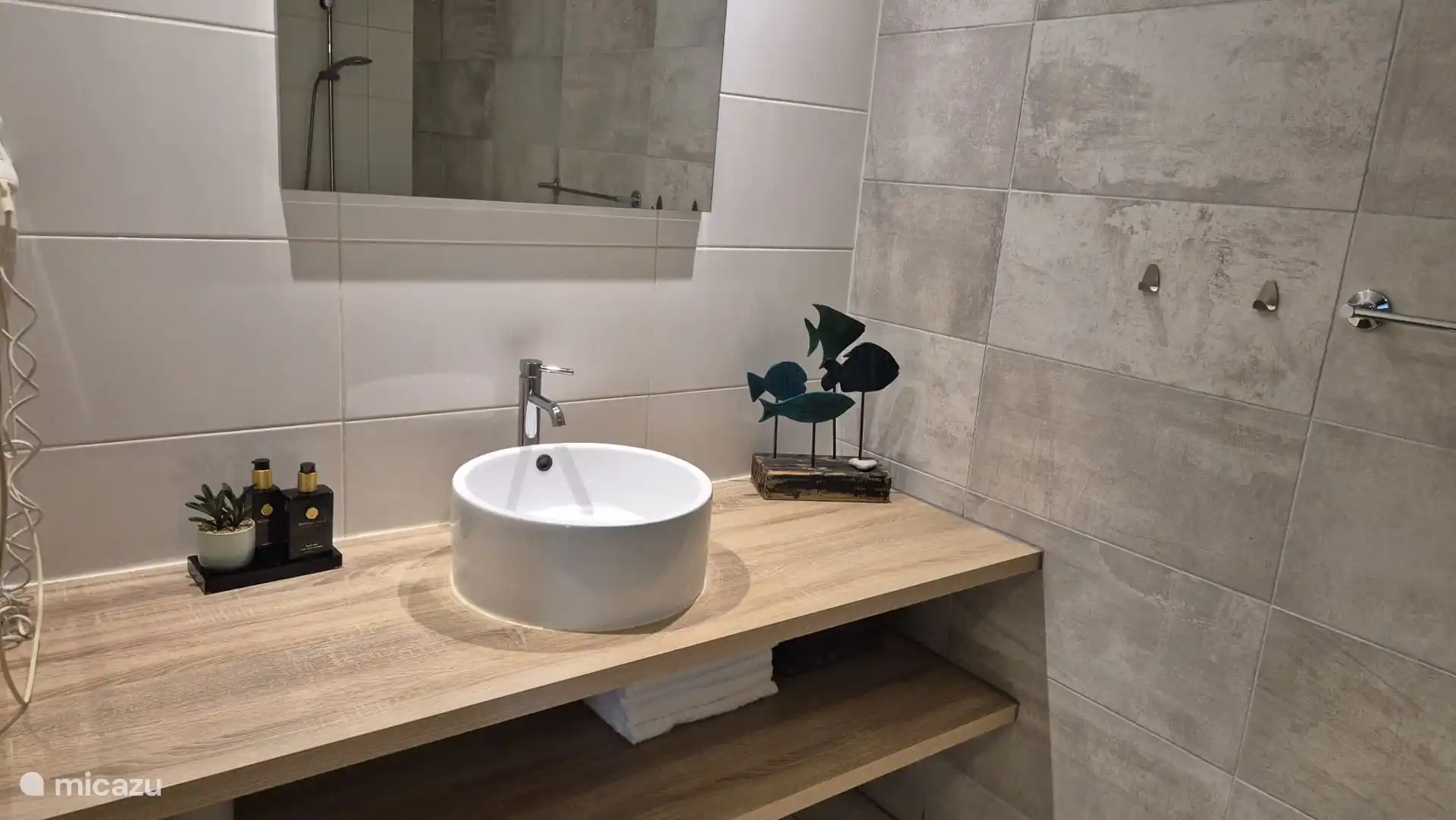 Badezimmermöbel mit warmem Holzlook und Stauraum unten. Ausgestattet mit einer runden, oberflächenmontierten Schale aus weißer Keramik und einem modernen Chromhahn. Ein gemütlicher Blickfang!