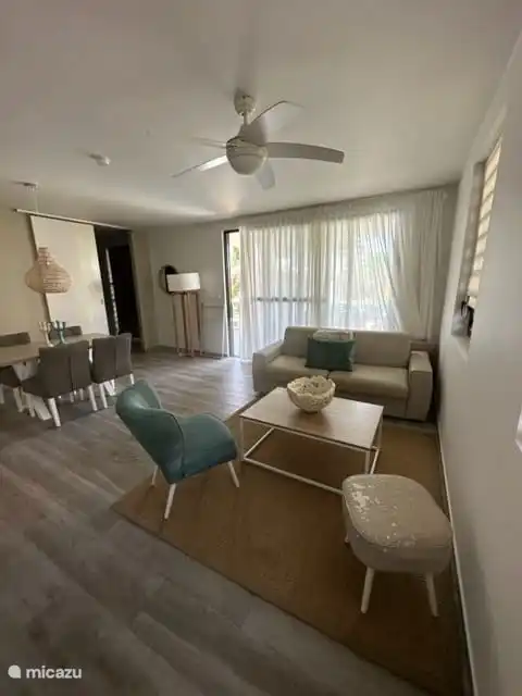 De huiskamer met openkeuken, eettafel met 4 stoelen en een 2 persoonsbank met salontafel en losse stoel