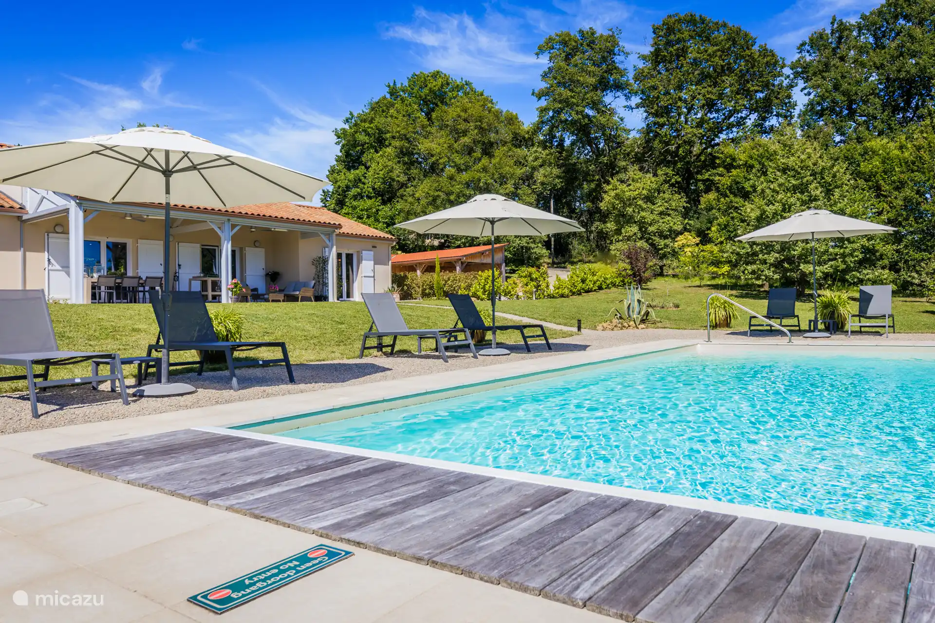 Liegestühle, Sonnenschirme und Tische am Pool