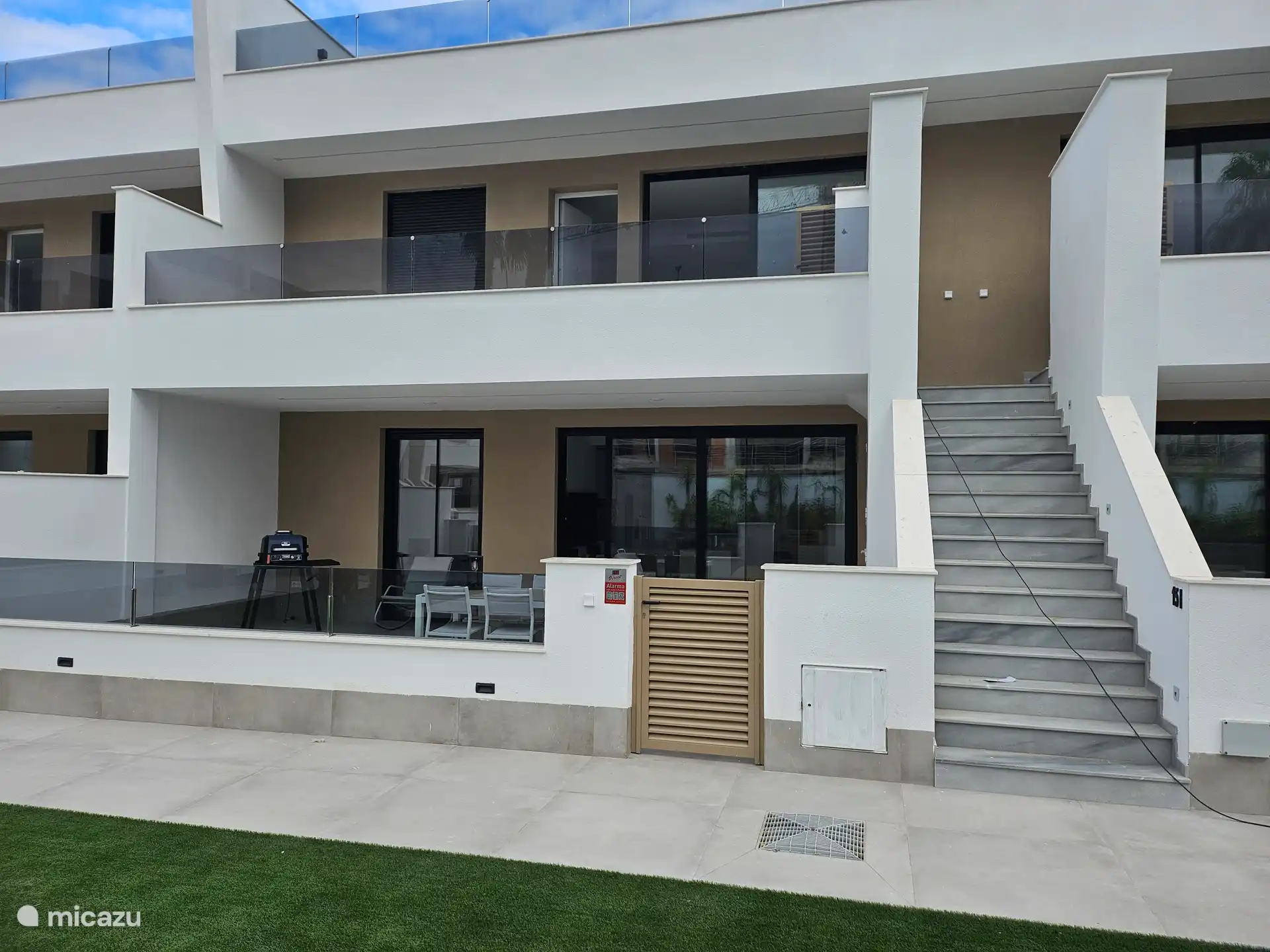 Terrasse mit Gartentisch, Stühlen, Sonnenliegen und Grill. Die Terrasse hat Zugang zum Pool.