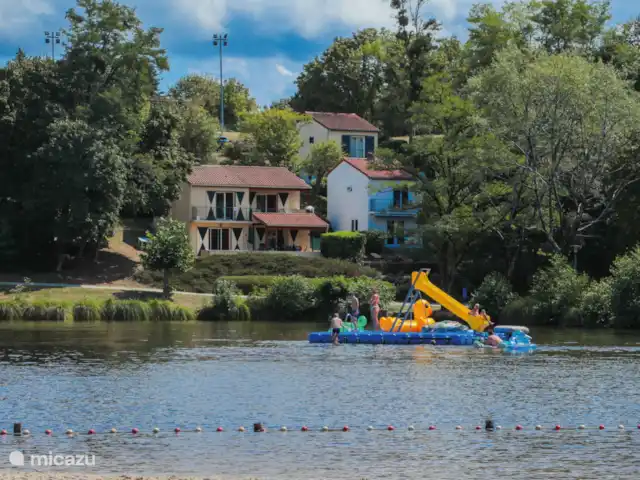 Château Corma | France, Charente, Écuras - maison de vacances Lac de baignade vu de la plage, la plage est équipée de transats, de parasols fixes et de toilettes.