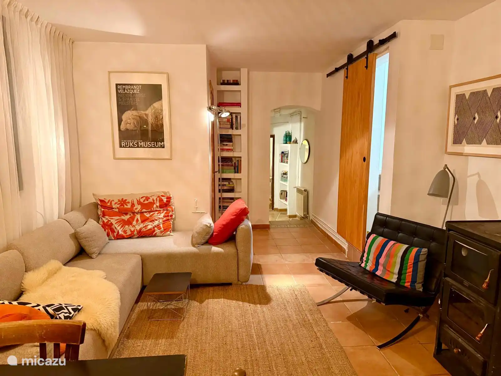 le salon avec passage vers la salle de bain et deux chambres à l’arrière, escalier droit vers la troisième pièce. À l’avant, le poêle à bois qui allume le chauffage central.