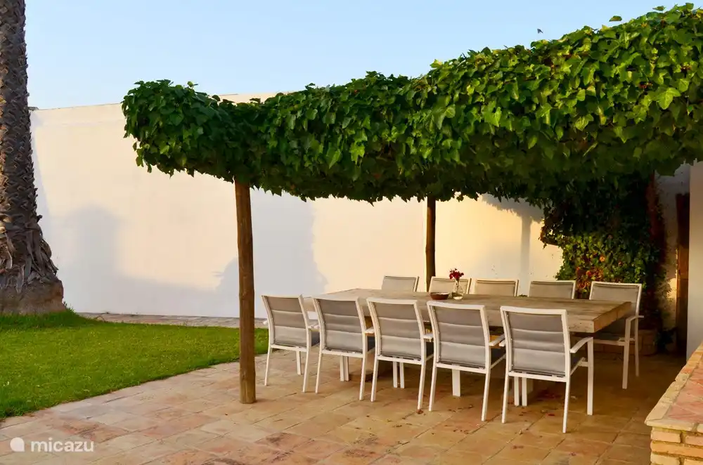 Una gran mesa de comedor cerca de la cocina bajo el porche.